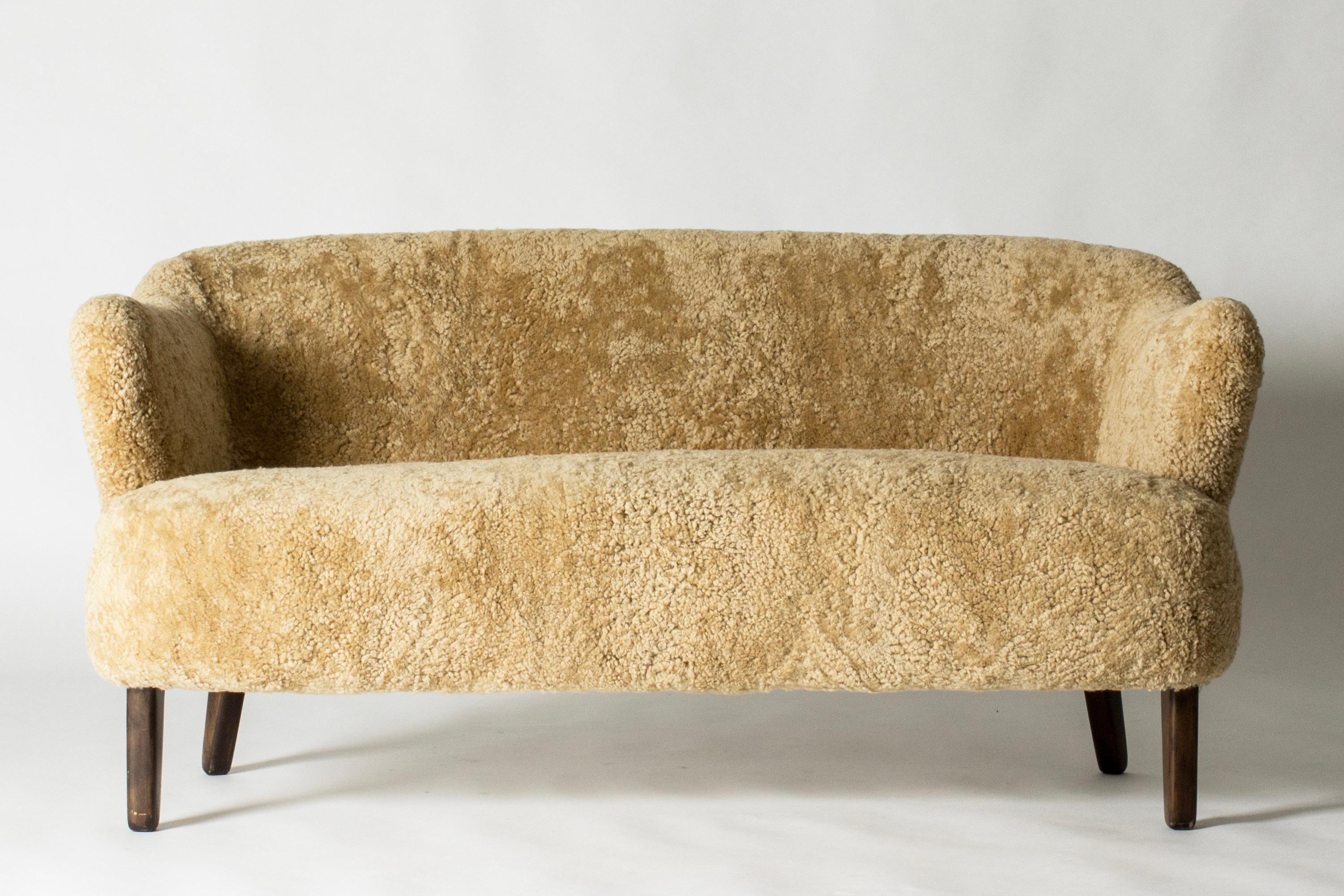 Beautiful “Ingeborg” sofa by Flemming Lassen, with curvesome forms. Designed in 1940 and named after his mother, the artist Ingeborg Winding. Upholstered with caramel colored sheepskin, stained wood legs.