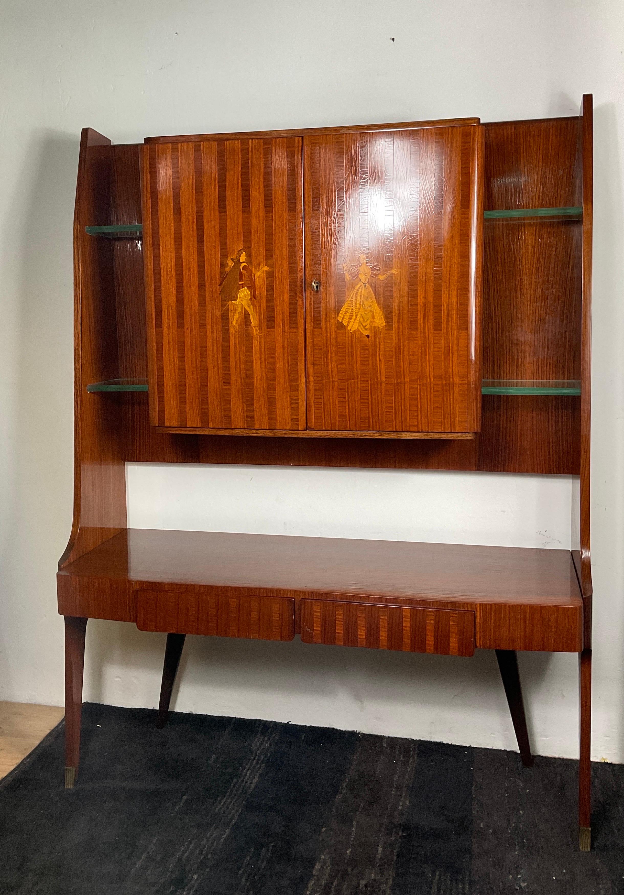 Moveable bar by Vittorio Dassi from the 50s. In maple and mahogany wood, doors with inlaid decorations, with two drawers and thick crystal shelves both outside and inside. Rear legs and drawers in dark colour, bridge structure, brass tips. In good