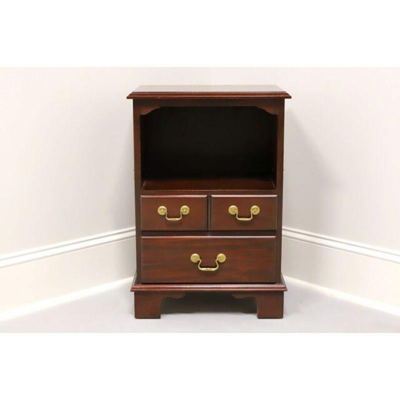A Traditional style nightstand, unbranded, on par with high end furniture makers such as Thomasville and Henredon. Inlaid mahogany with brass hardware and bracket feet. Features two dovetail drawers below open storage area and side handles. Made in