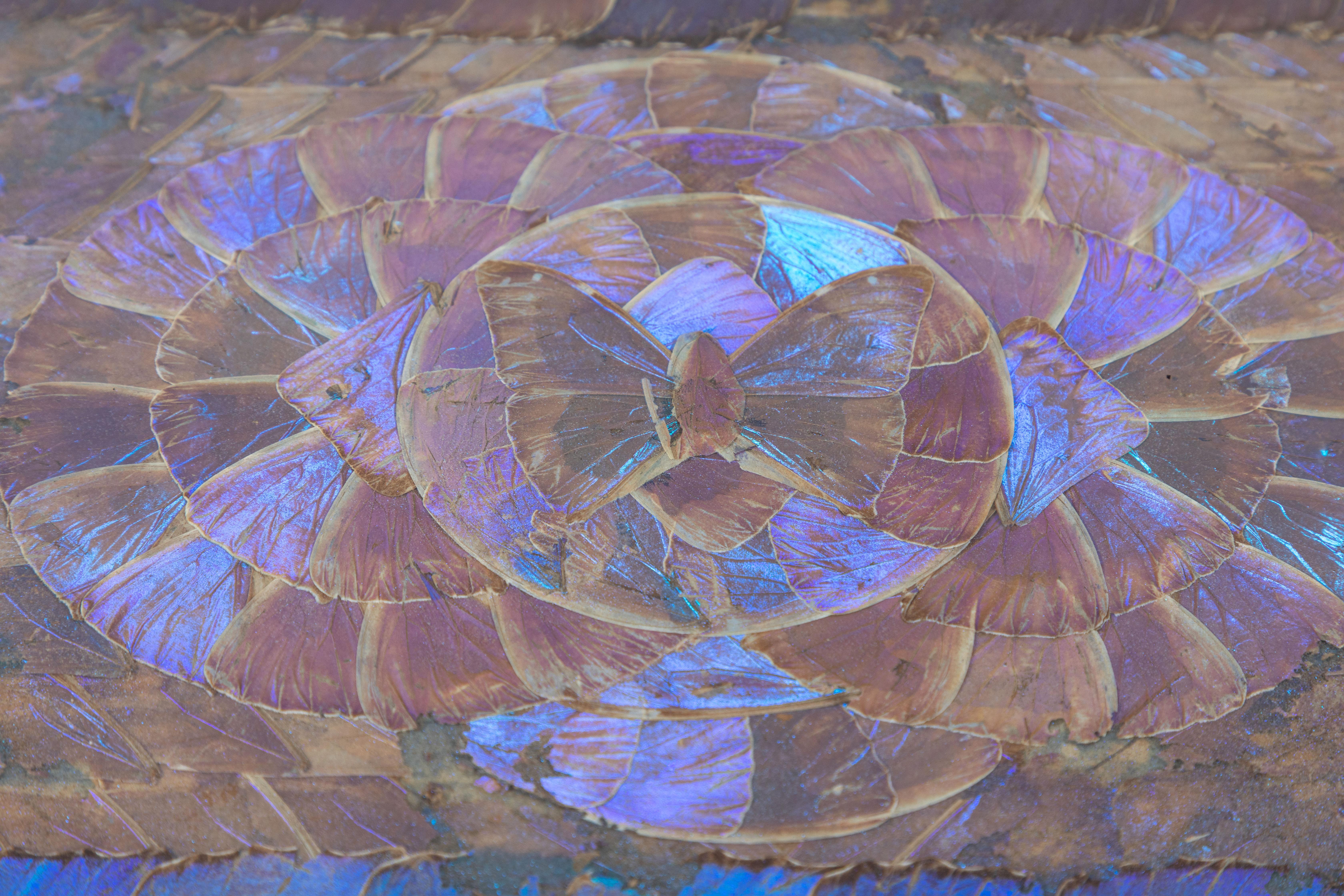 Dieses alte Holztablett zeigt ein geometrisches Muster aus den Flügeln des leuchtend schillernden Blauen Morpho-Schmetterlings. Drehen Sie das Tablett und beobachten Sie:: wie die Flügel von violettblau zu staubigbraun schimmern. Die Intarsien und