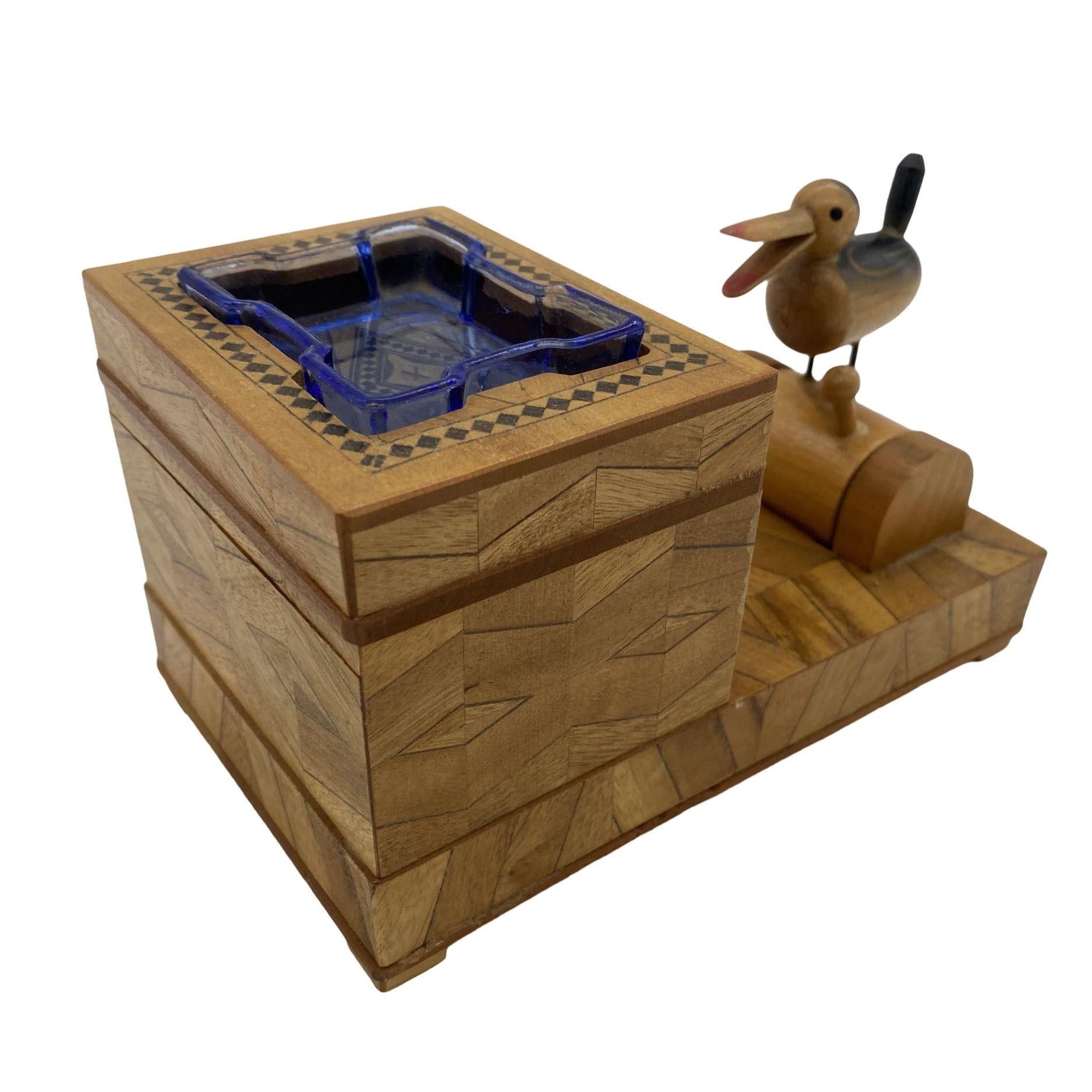 Vintage wooden cigarette box, cigarette holder, and ashtray with mechanical bird. simply push down the lever and a cigarette will be dispensed as a bird picks up the cigarette out of the box. 

The carved box is decorated with geometric