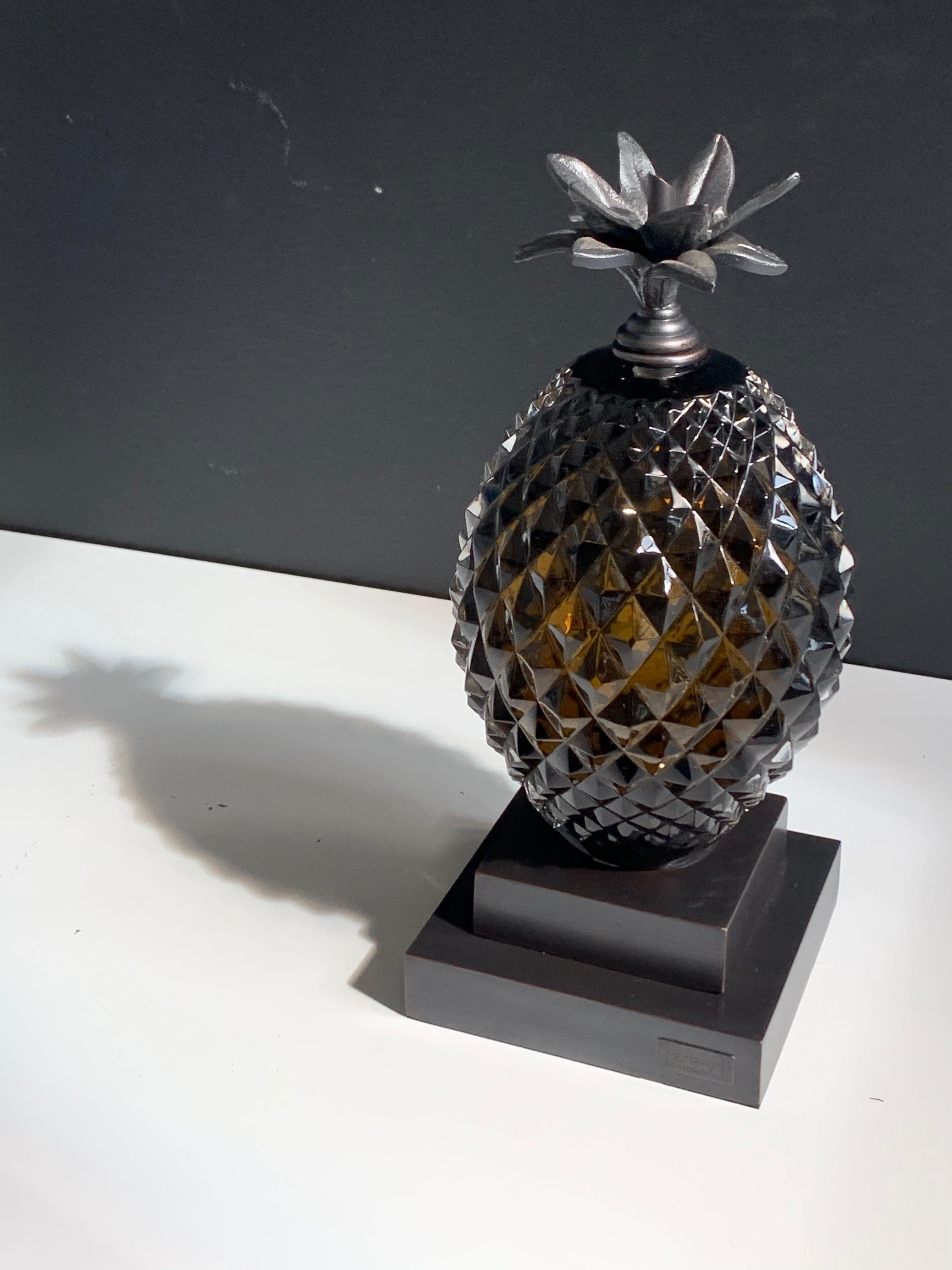 Mouth blown and hand carved olive color glass pineapple coupled with cast metal stand and leaf motif to work as a bookend or an accent piece in timeless interiors.