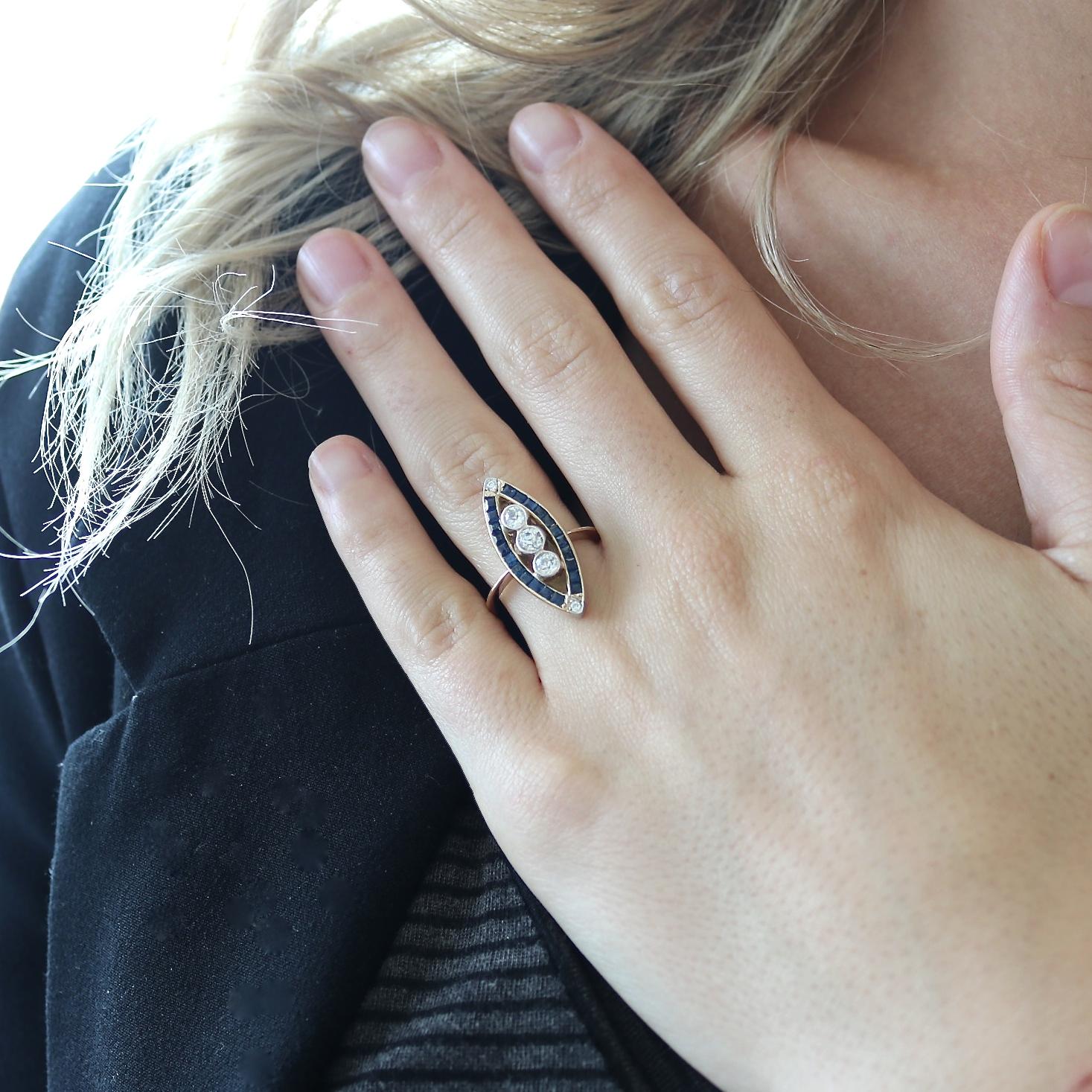 Victorian style that is both timeless and graceful. Featuring three old European cut diamonds weighing approximately 0.20 carats each set among rows of navy blue natural sapphires. Crafted in 18k yellow gold. Ring size 7-1/4 and can easily be