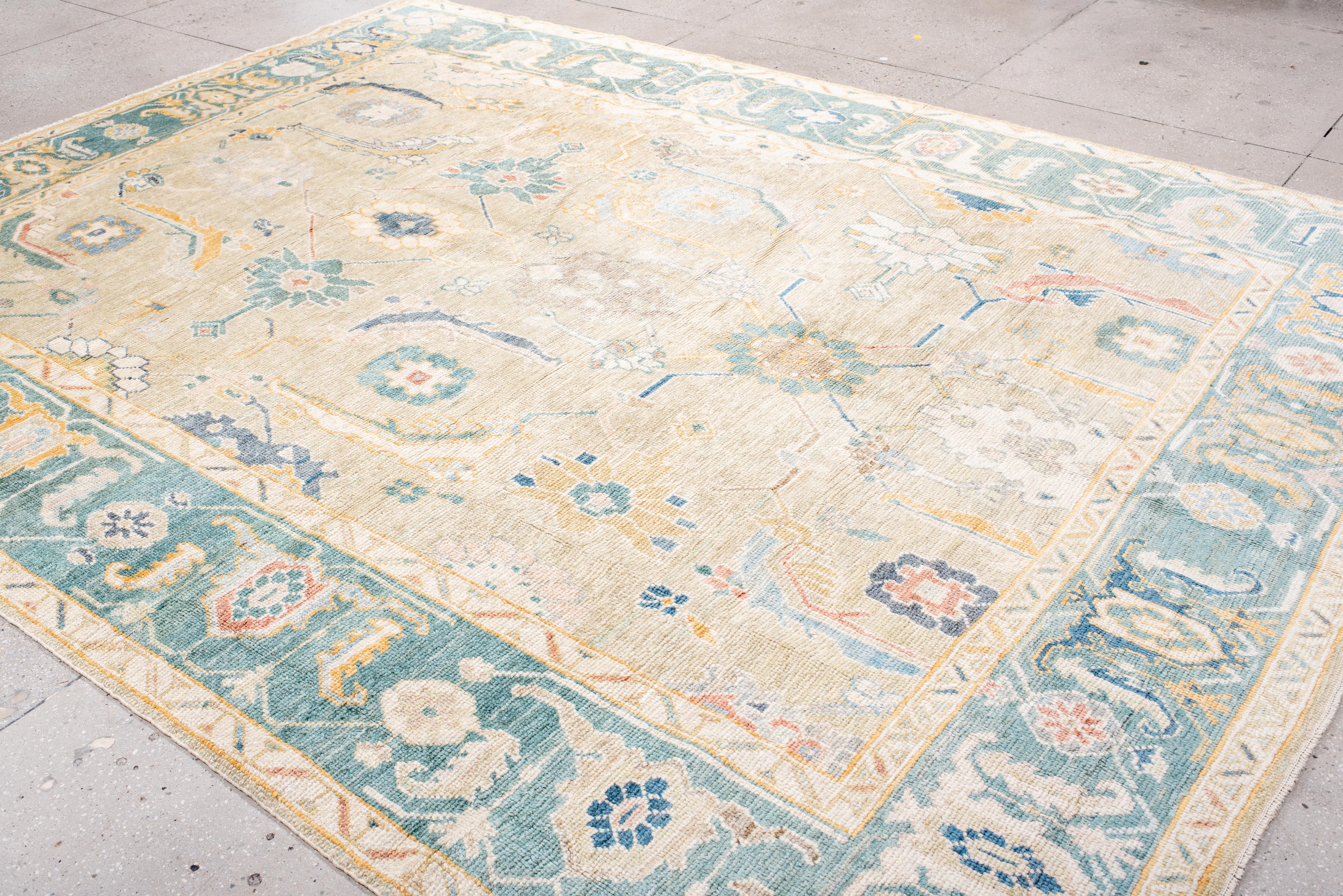 Questo tappeto Oushak senza tempo, con una patina splendidamente invecchiata, unisce l'artigianato tradizionale a un'eleganza morbida e vissuta. I suoi intricati motivi floreali e i dettagli geometrici sono delicatamente incorniciati da un ampio