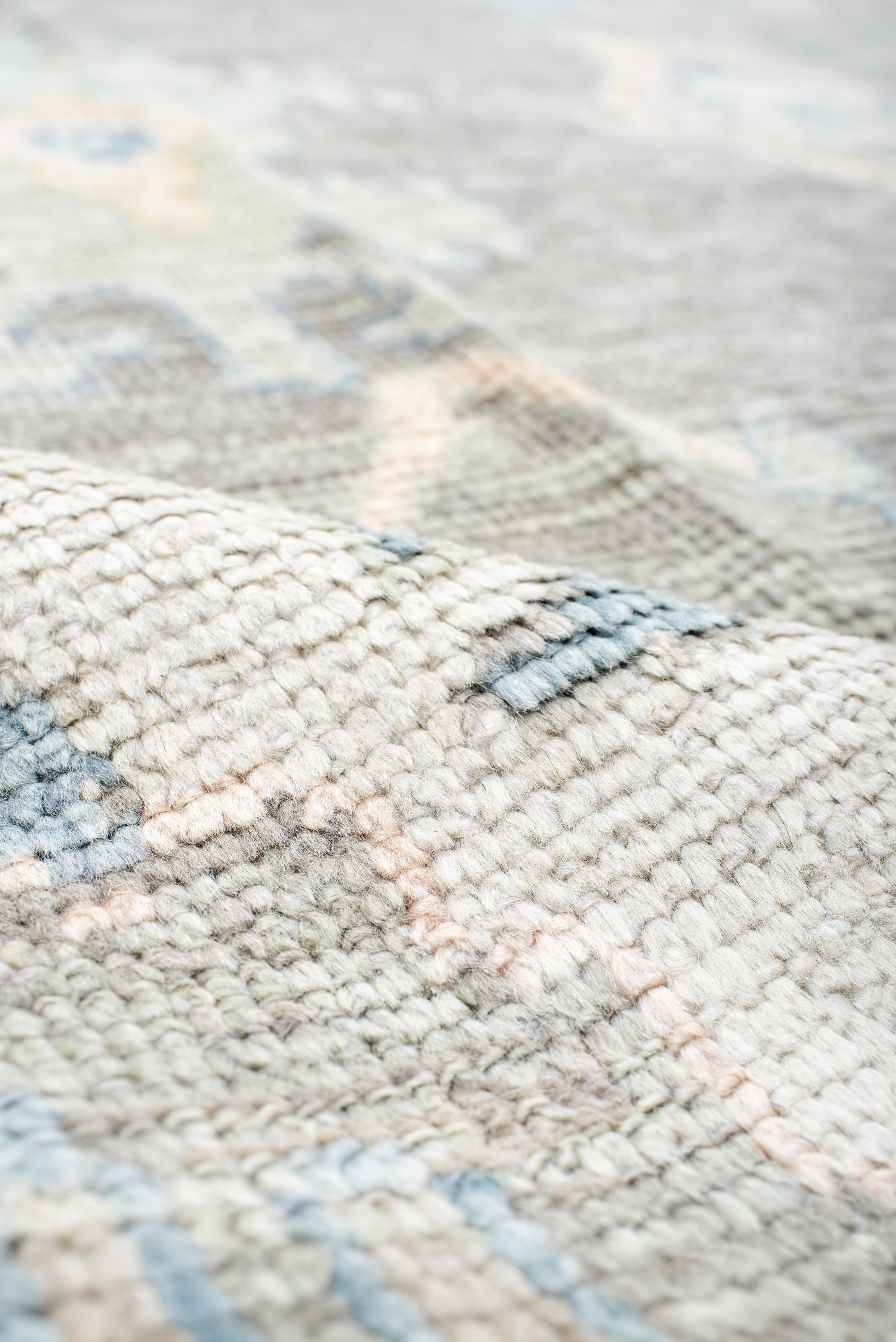 A masterful expression of balance and scale, this grand Oushak rug features an open, free-flowing arrangement of abstract floral and tribal motifs. The generous proportions allow the design to unfold with an effortless rhythm, while the softly faded