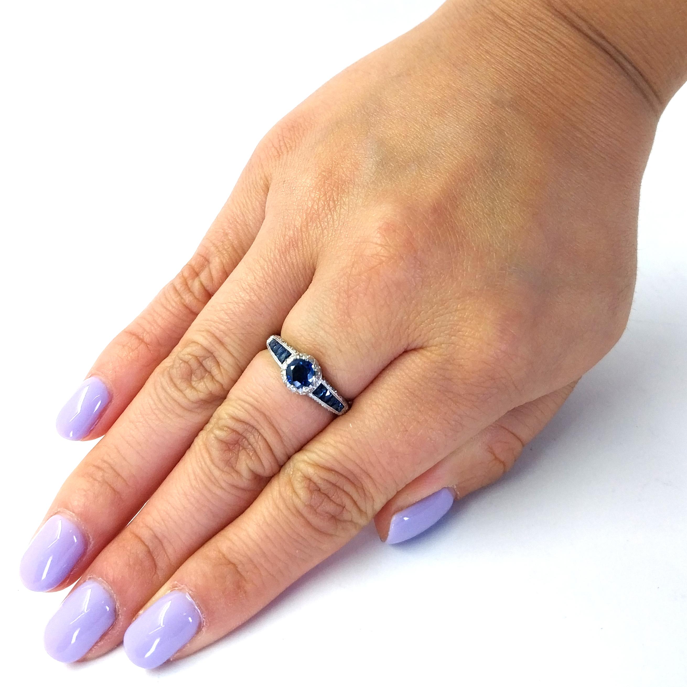 18 Karat White Gold Ring Featuring 11 Round and Calibre Cut Sapphires Totaling Approximately 0.75 Carats Accented by 36 Round Brilliant Cut Diamonds of VS Clarity and G Color Totaling Approximately 0.25 Carats. Three Sided Design with Millgrain and