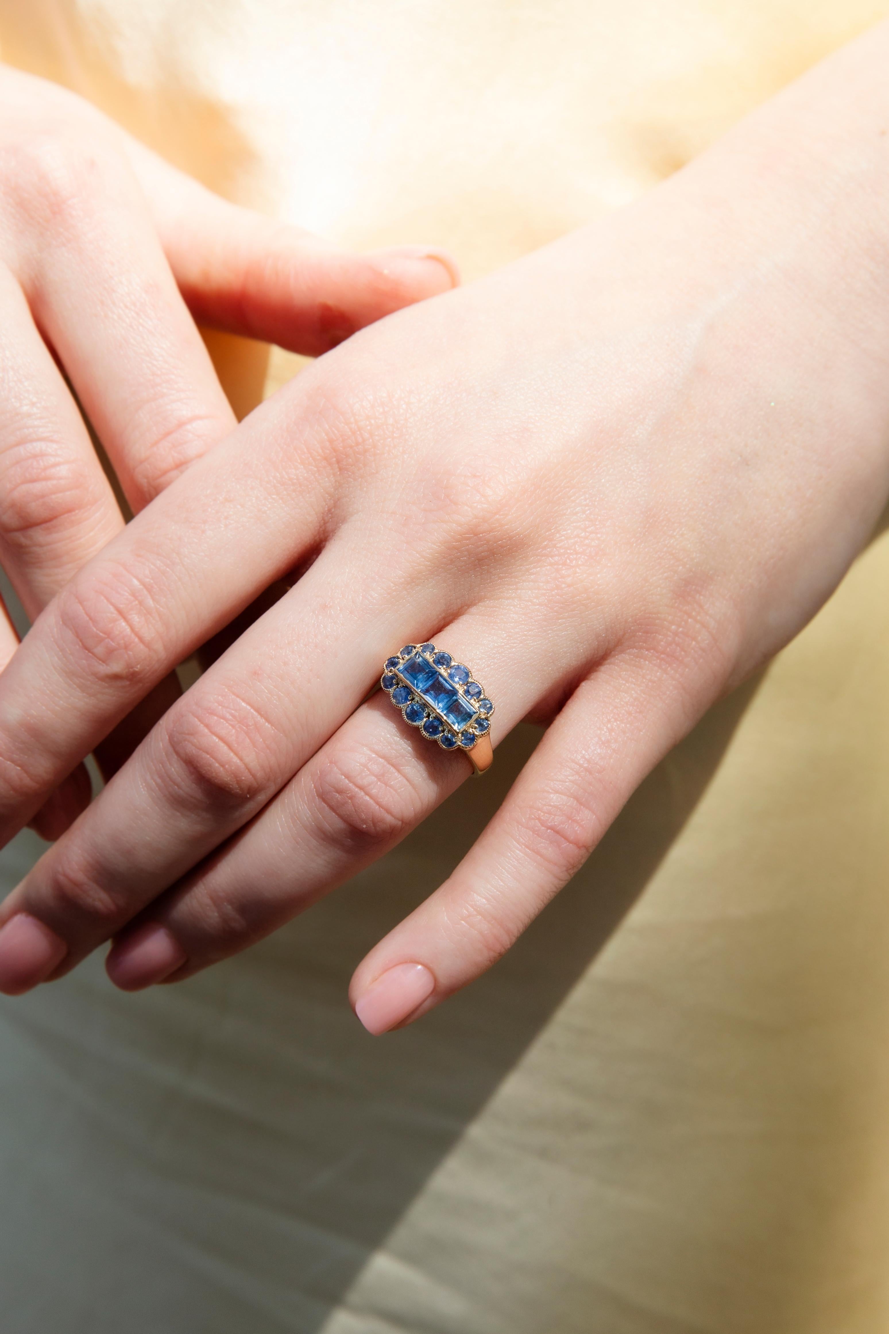 The Ingrid Ring is a nod to a star of yesteryear who graced the silver screen with irresistible allure and boundless grace. Her bright blue square sapphire trio, set within a cloud-like sapphire border, evokes a world of glitz and glamour where red
