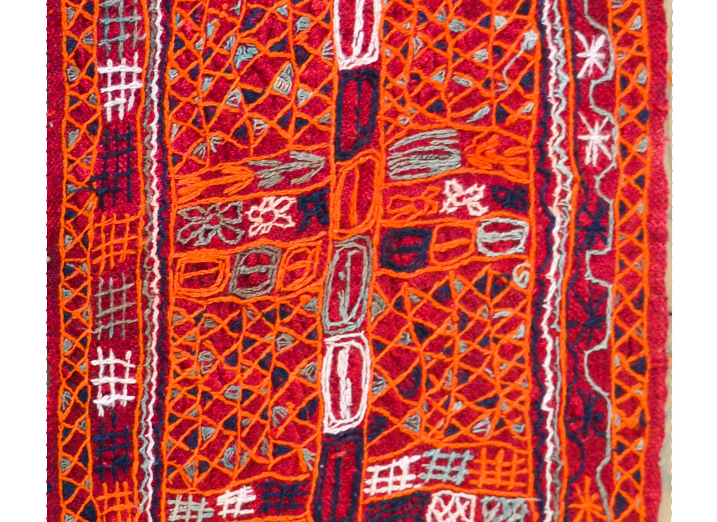 A striking late 20th century Iraqi handwoven crimson wool panel with all-over embroidered geometric patterns stitched in brilliant orange, indigo, white, and gray cotton thread.