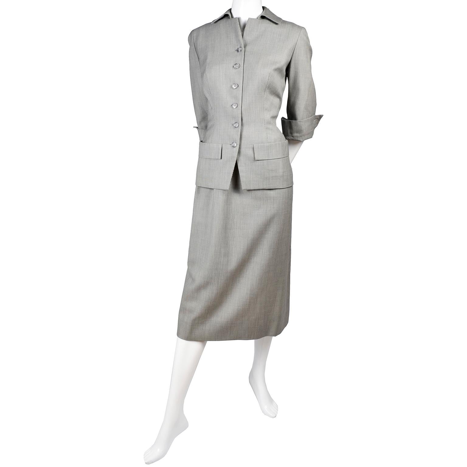 1950's Irene Lentz exclusively for Gunther Jaeckel 2 piece blazer and skirt suit in a lovely gray lightweight wool, lined in a luxurious pink silk.  The jacket of the suit buttons up the front, has two flap pockets, 3/4 length sleeves with upturned
