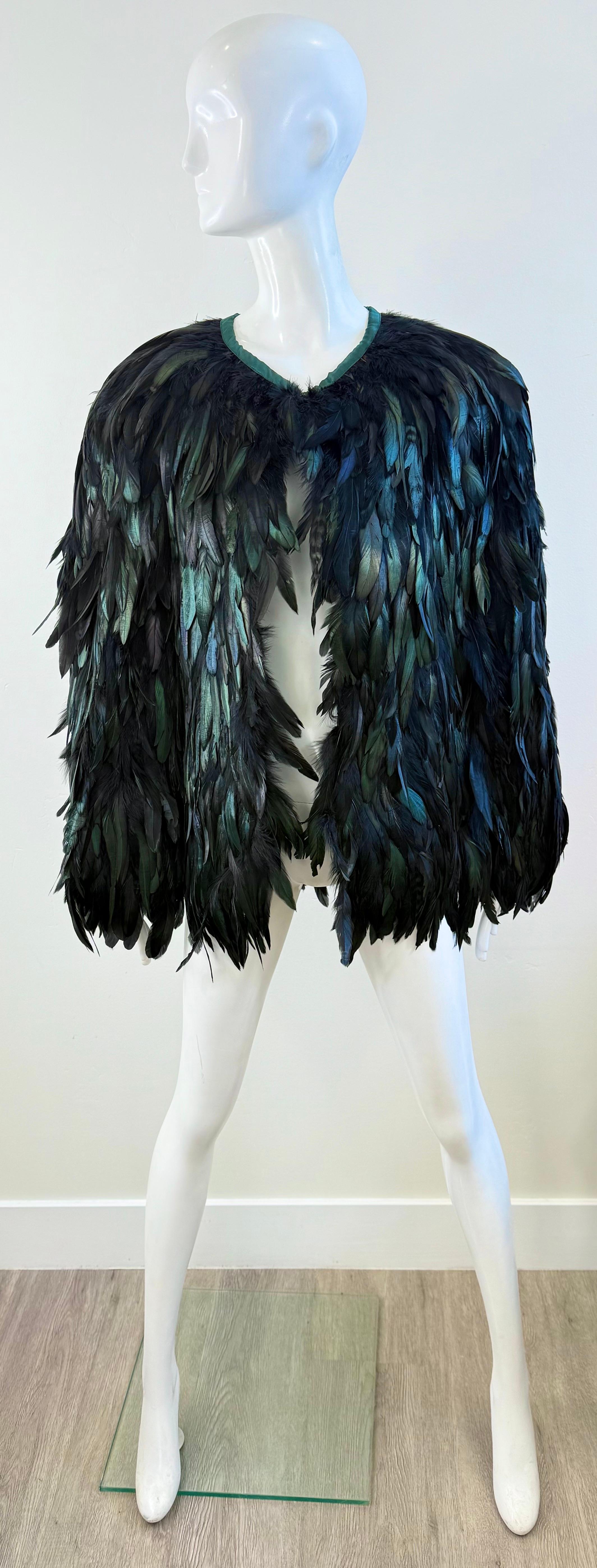 Un mantello di piume vintage mozzafiato in taglia unica, realizzato con strati di piumaggio iridescente nei toni scintillanti del nero, del verde smeraldo e del blu zaffiro. Le piume catturano la luce con una lucentezza luminosa, conferendo a questo