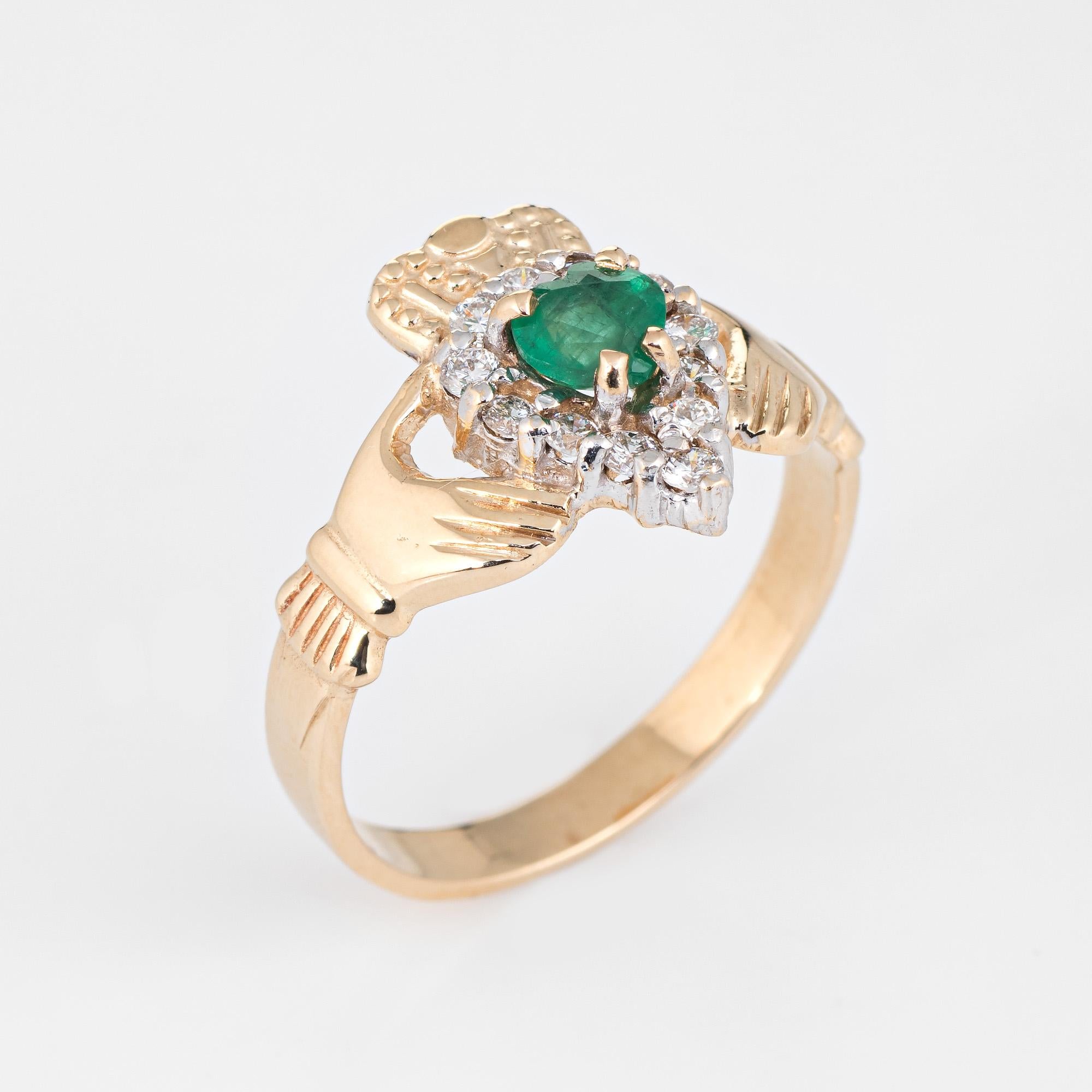 Finely detailed emerald & diamond Irish Claddagh ring crafted in 14k yellow gold. 

Centrally mounted heart cut emerald measures 5mm (estimated at 0.50 carats), accented with 12 estimated 0.03 carat round brilliant cut diamonds. The total diamond