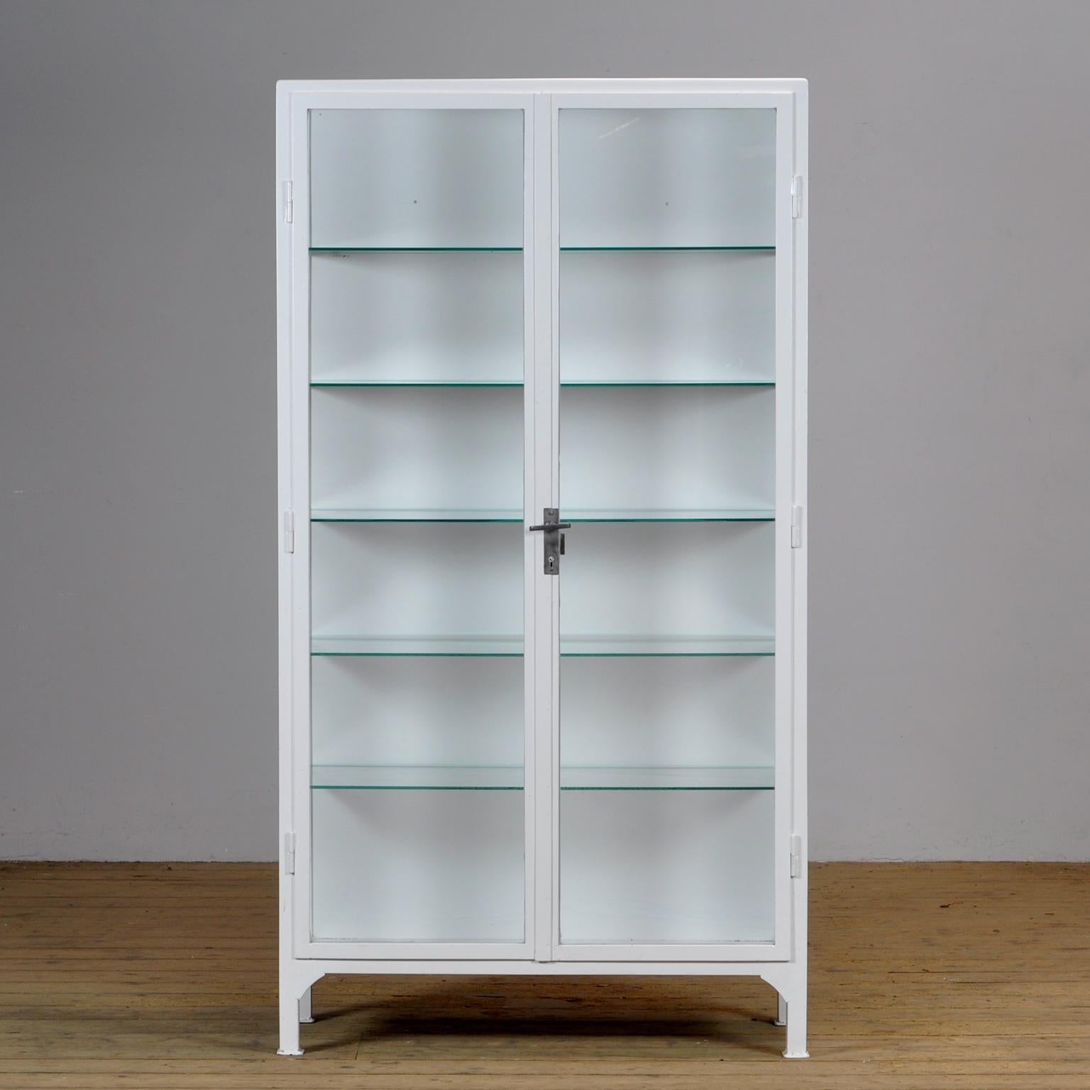 Polish medicine cabinet, produced in the 1960s. Made of iron and glass. The cabinet has recently been repainted and all the glass has been replaced. 5 new adjustable glass shelves on the inside. Heavy quality, the cabinet weighs approximately 80kg.