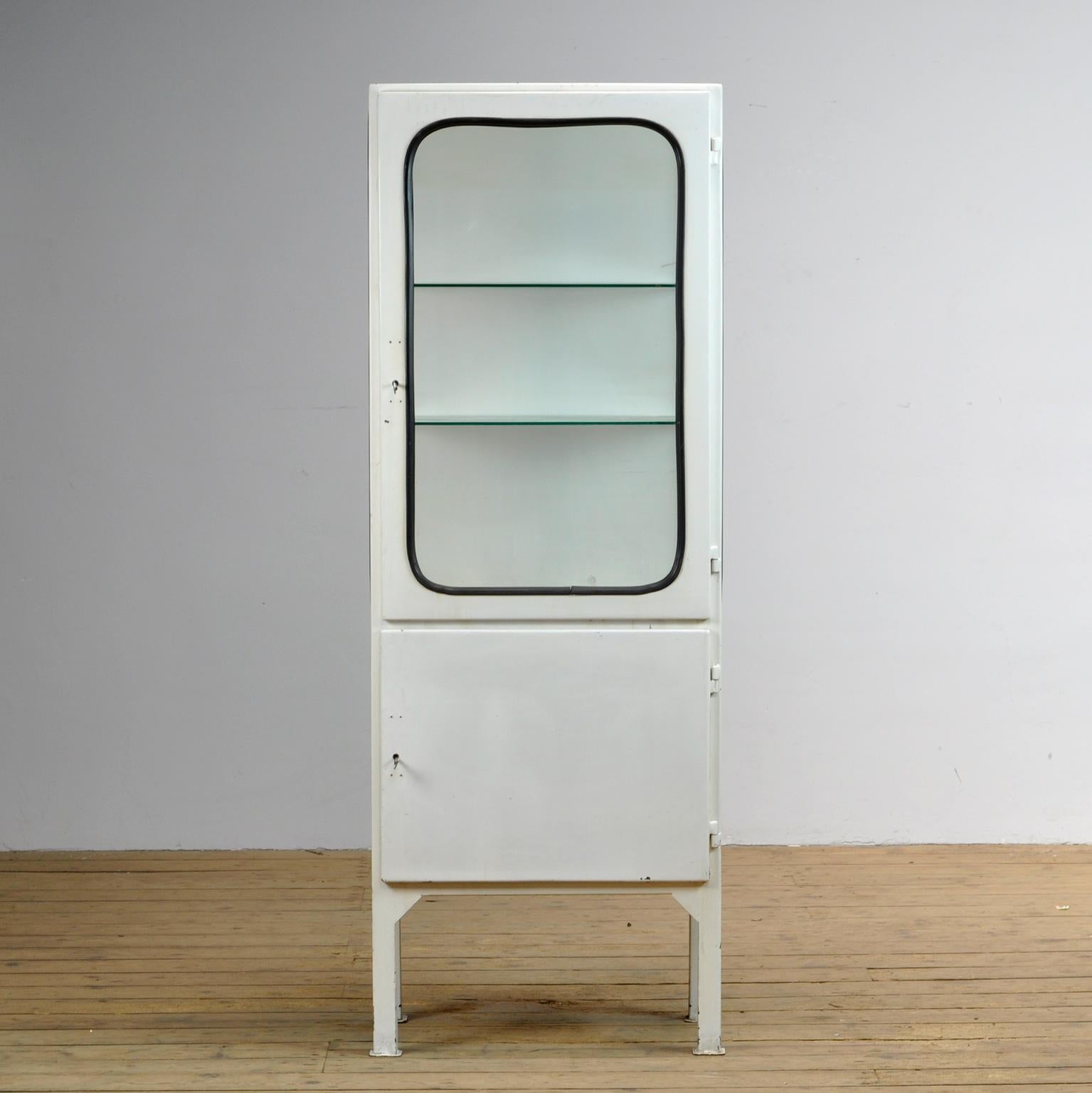  This medical cabinet was designed in the 1970s and was produced circa 1975 in hungary. It is made from iron and glass with new glass shelves. The glass is held by a black rubber strip. The cabinet features two adjustable glass shelves and
