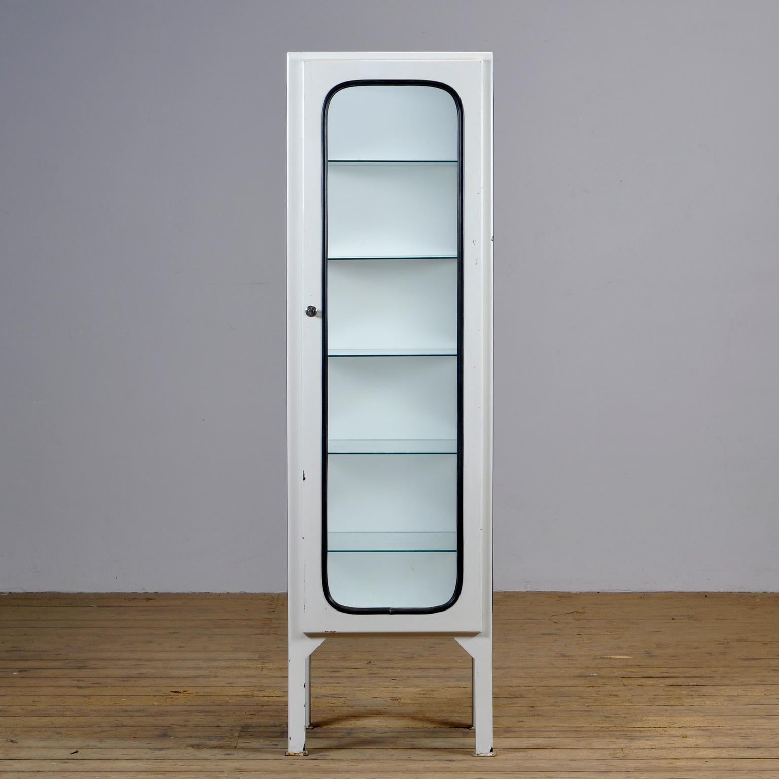This medical cabinet was designed in the 1970s and was produced circa 1975 in Hungary. It is made from iron and glass with new glass shelves. The glass is held by a black rubber strip. The cabinet features five adjustable glass shelves and a
