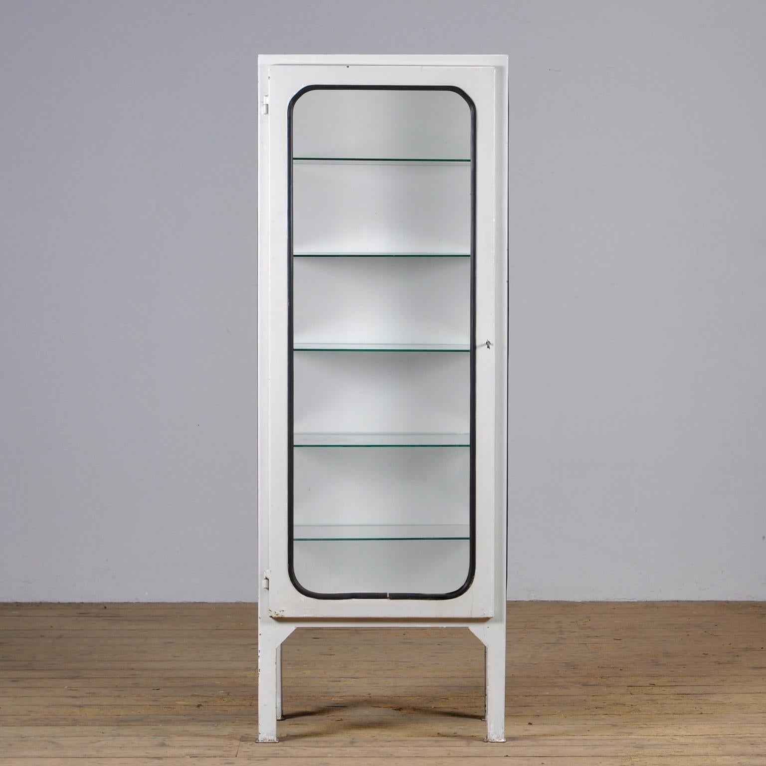 This medical cabinet was designed in the 1970s and was produced circa 1975 in hungary. It is made from iron and glass with new glass shelves. The glass is held by a black rubber strip. The cabinet features five adjustable glass shelves and a