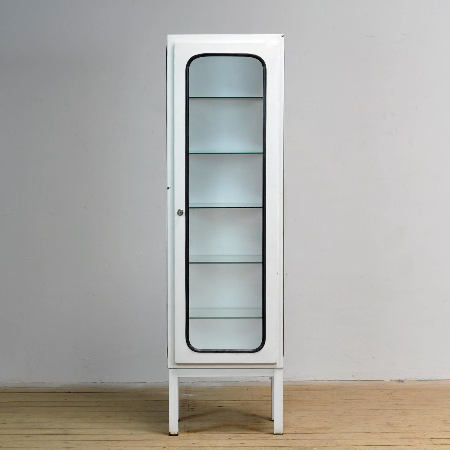 This medical cabinet was designed in the 1970s and was produced circa 1975 in hungary. It is made from iron and glass with new glass shelves. The glass is held by a black rubber strip. The cabinet features five adjustable glass shelves and a