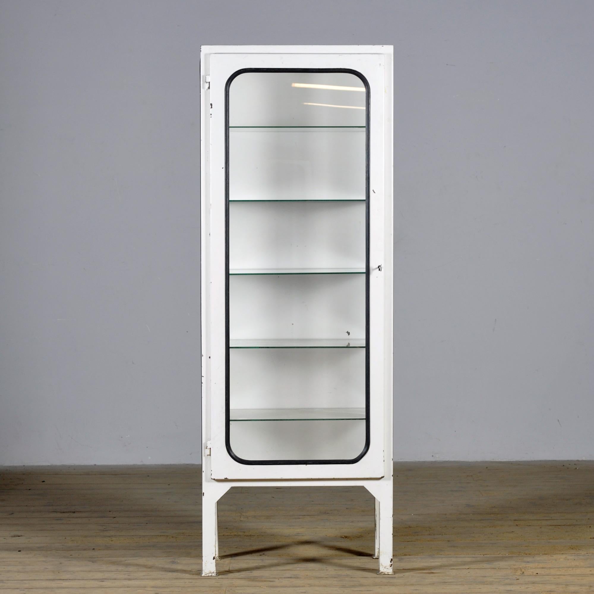 Dieser medizinische Schrank wurde in den 1970er Jahren entworfen und um 1975 in Ungarn hergestellt. Er ist aus Eisen und Glas mit neuen Glasböden gefertigt. Das Glas wird von einem schwarzen Gummistreifen gehalten. Der Schrank verfügt über fünf