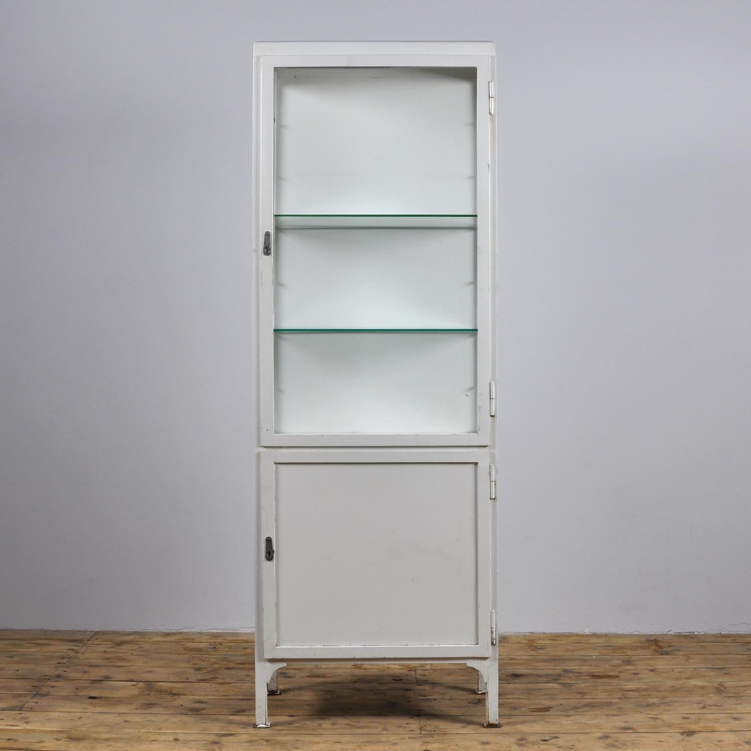 Medical cabinet from the Czech republic, produced in the 1960s. The cabinet is made of iron and (antique) glass. With two (adjustable) glass shelves. Behind the bottom door a steel shelf.