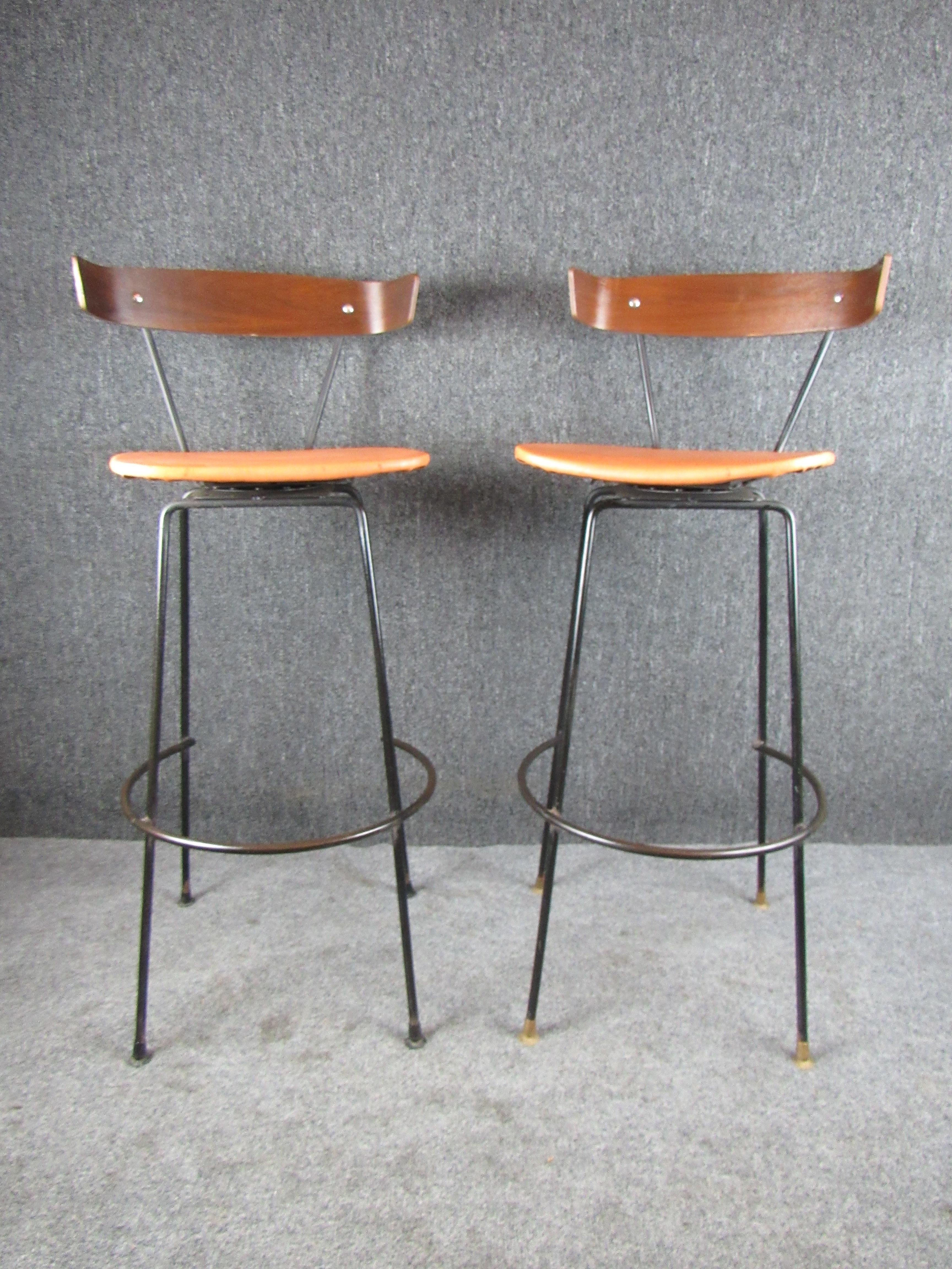 Take home a wonderful example of authentic American Mid-Century Modern design with these endlessly charming wrought iron + walnut barstools by Clifford Pascoe. A sturdy metal base supports a swiveling seat with contoured bentwood backrests.