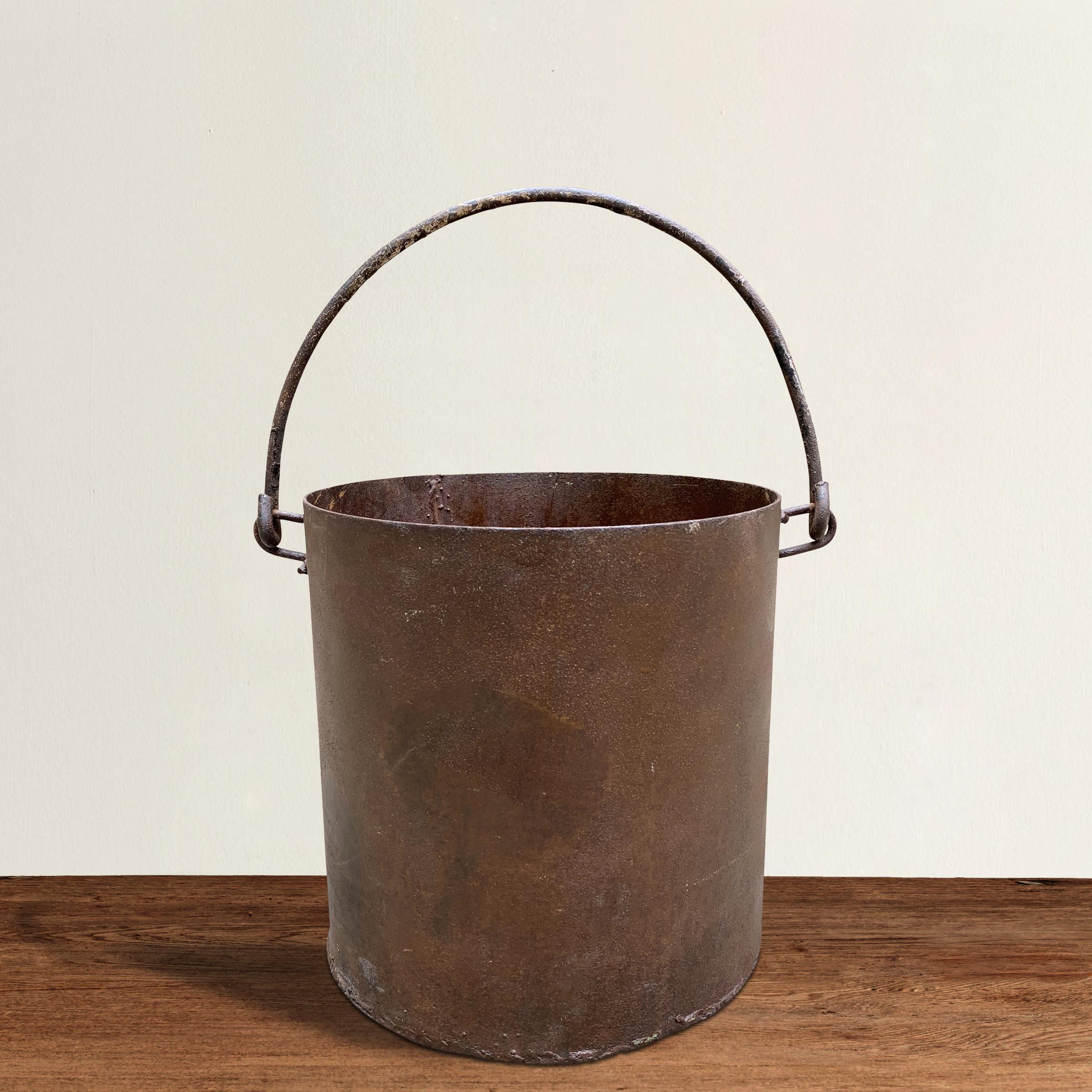 A stoic vintage iron bucket with a curved handle, and perfect for use as a waste paper basket in your powder room, office, or filled with ice and used to chill wine at your next fête.