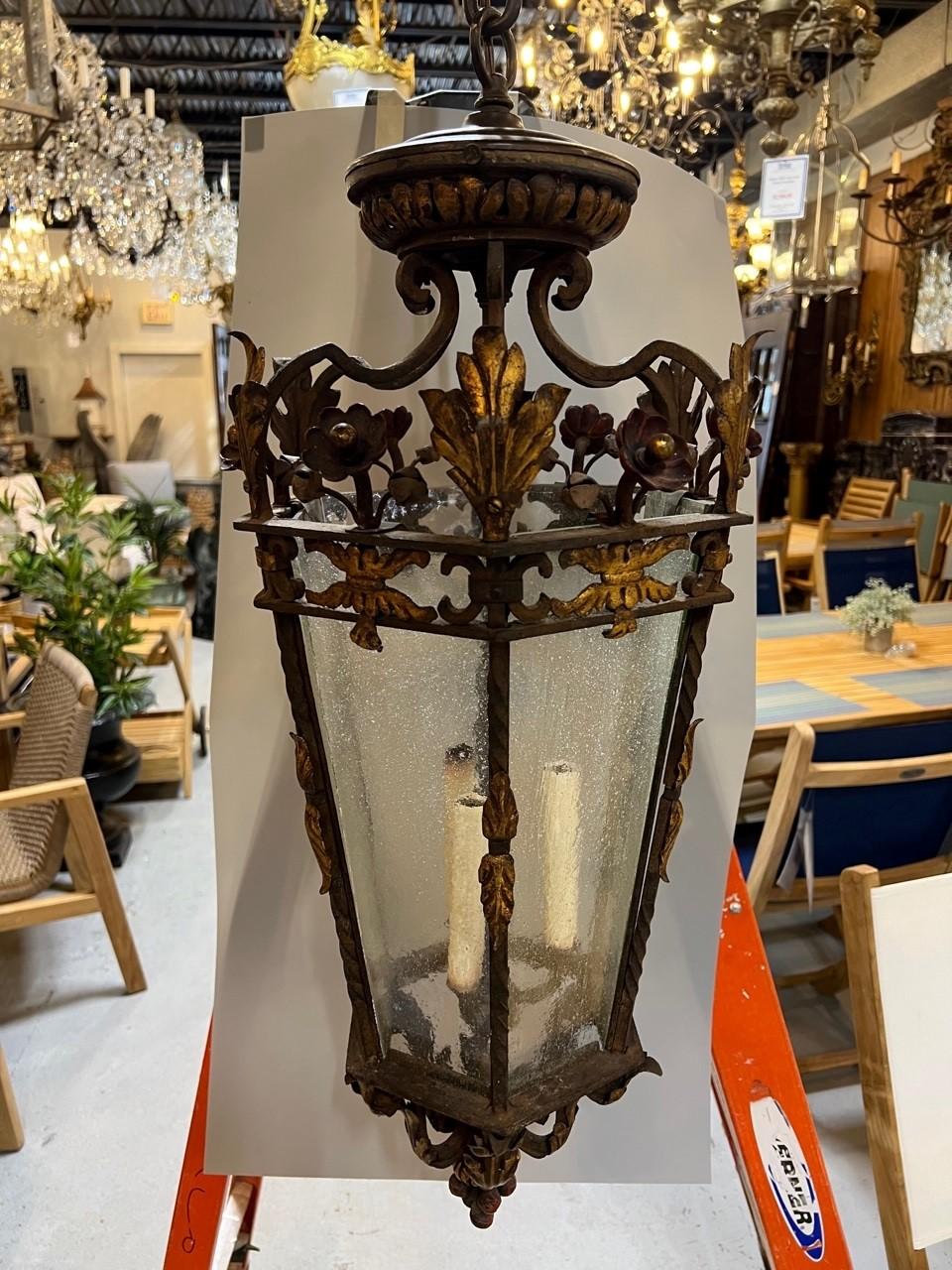 Amazing decorative iron lantern chandelier with six bubble glass panels, acanthus leaves and flowers. The gold paint on the acanthus leaves and all the decorative details looks great. The lantern comes with a ceiling cap and 45