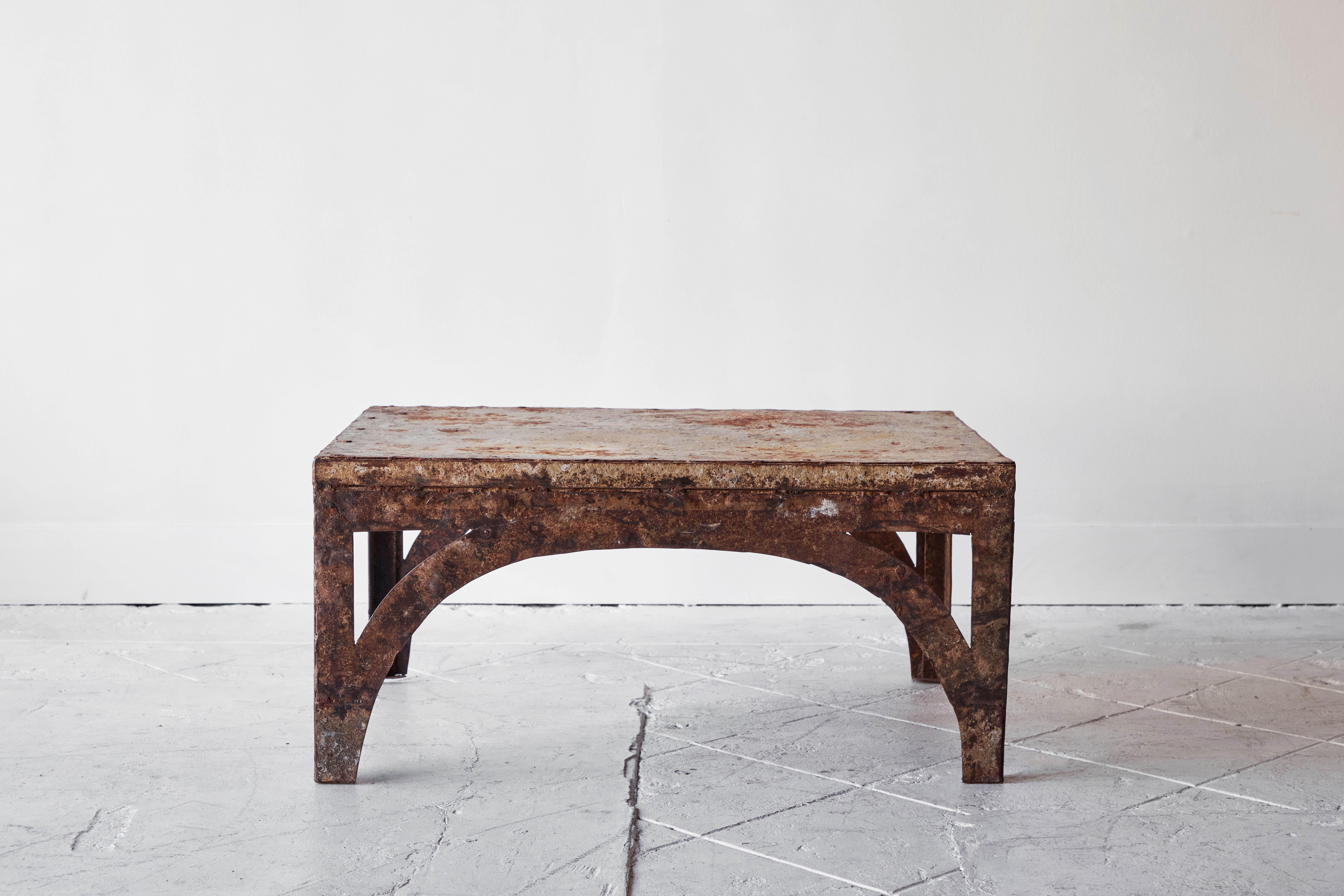 This industrial iron coffee table features arched legs and a perfectly chipped paint and rust finish that only time can bestow. This table is the perfect coffee table for any room.