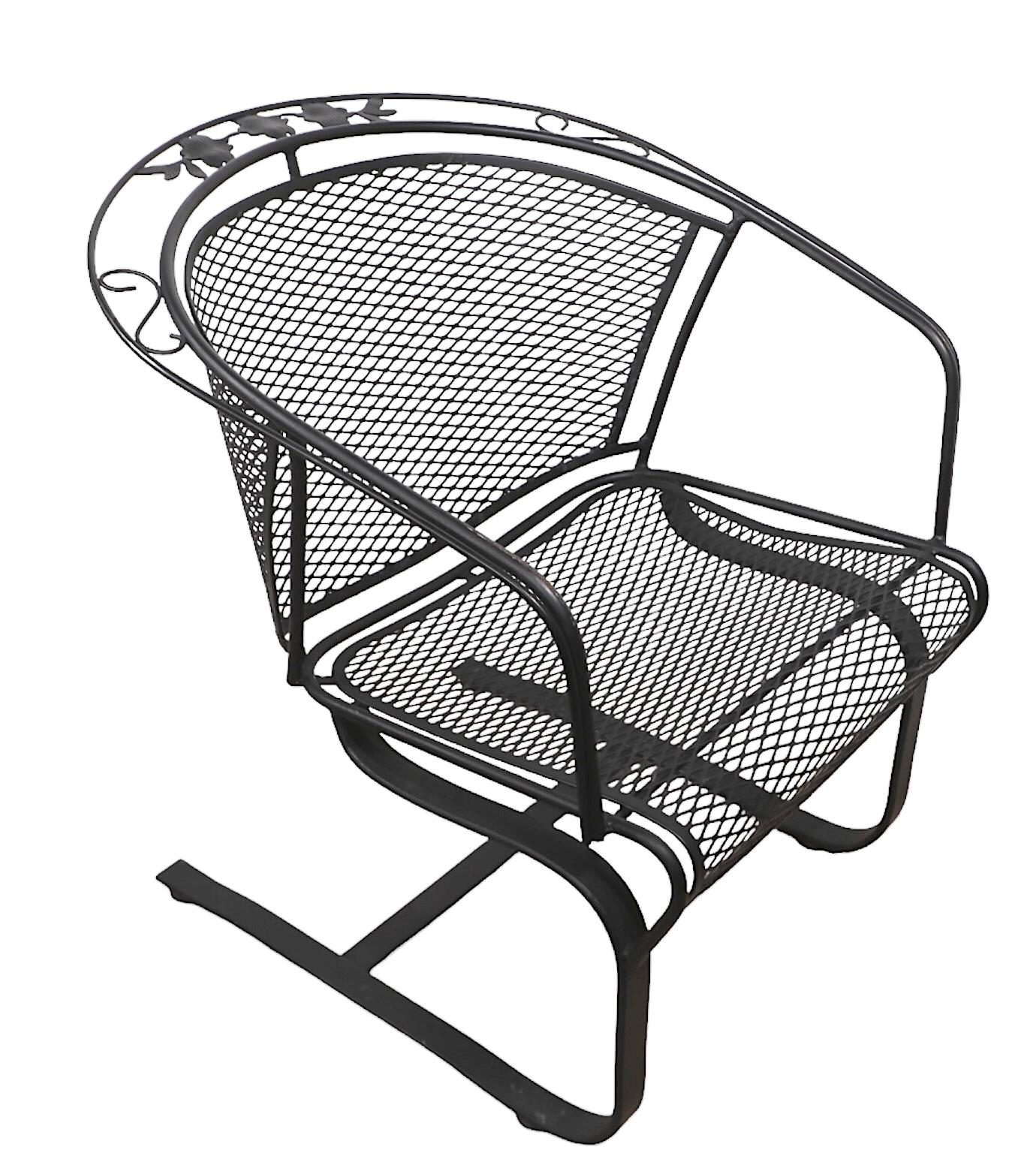 Sexy and stylish cantilevered wrought iron and metal mesh lounge, dining chair, attributed to the Woodard Furniture Company, circa 1960/70's. The chair features a spring base, which supports the metal mesh seat and curved backrest. The top of the