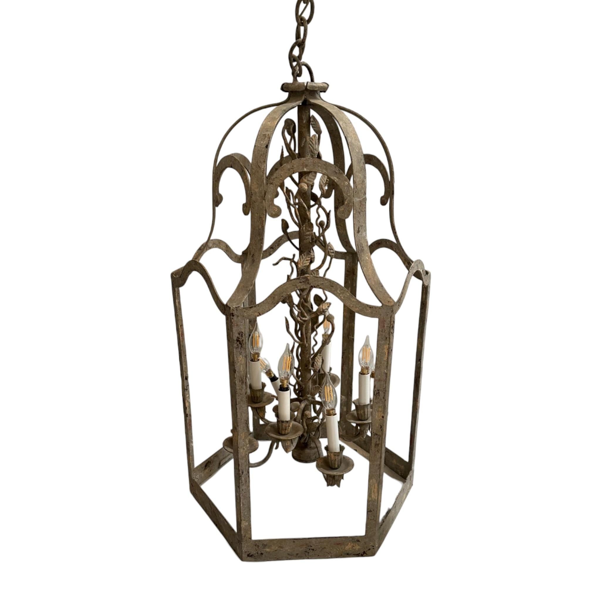 This Vintage Iron Lantern Chandelier is a special find that features delicate candelabra-style lamps nestled within an iron canopy and intricate leaf detailing.

The chandelier is a special find that would warmly illuminate intimate dining