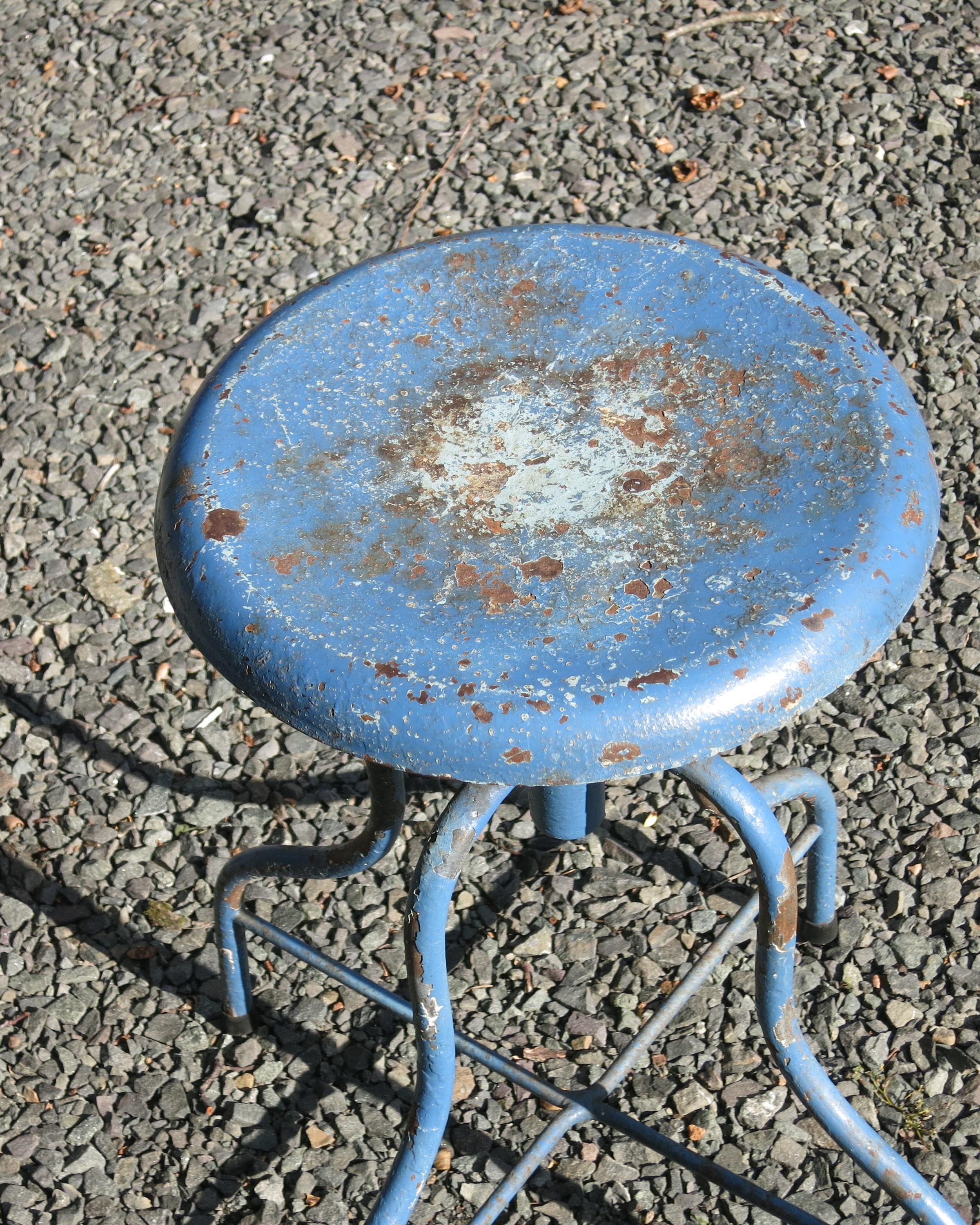 Vintage medical stool painted blue with losses and rust. It raises from 18