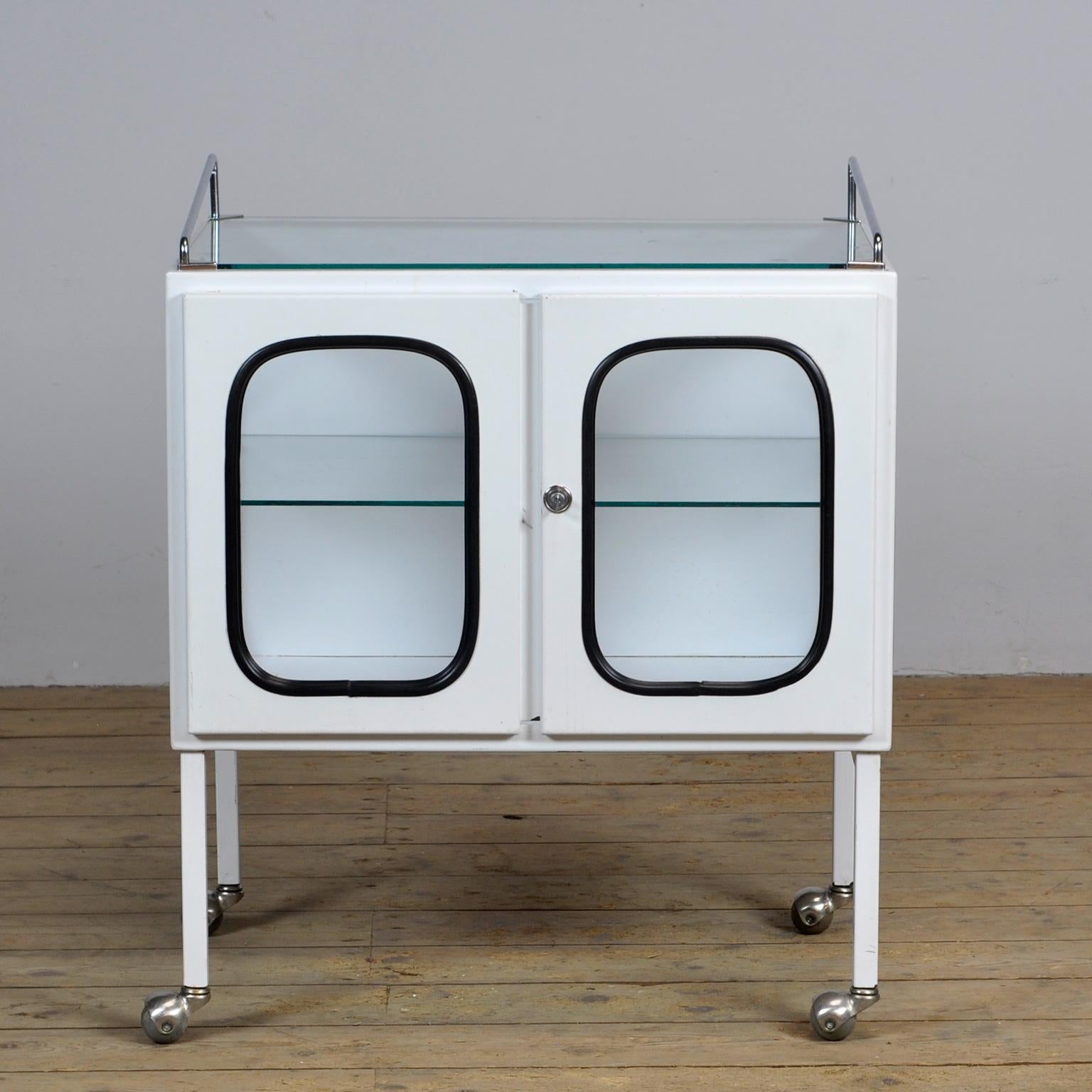 Vintage medical trolley in good condition. Made of iron and glass that is clamped in the steel by a rubber strip. The doors open smoothly and wheels are functioning perfectly. The trolley is from the 70s and is produced in hungary.
