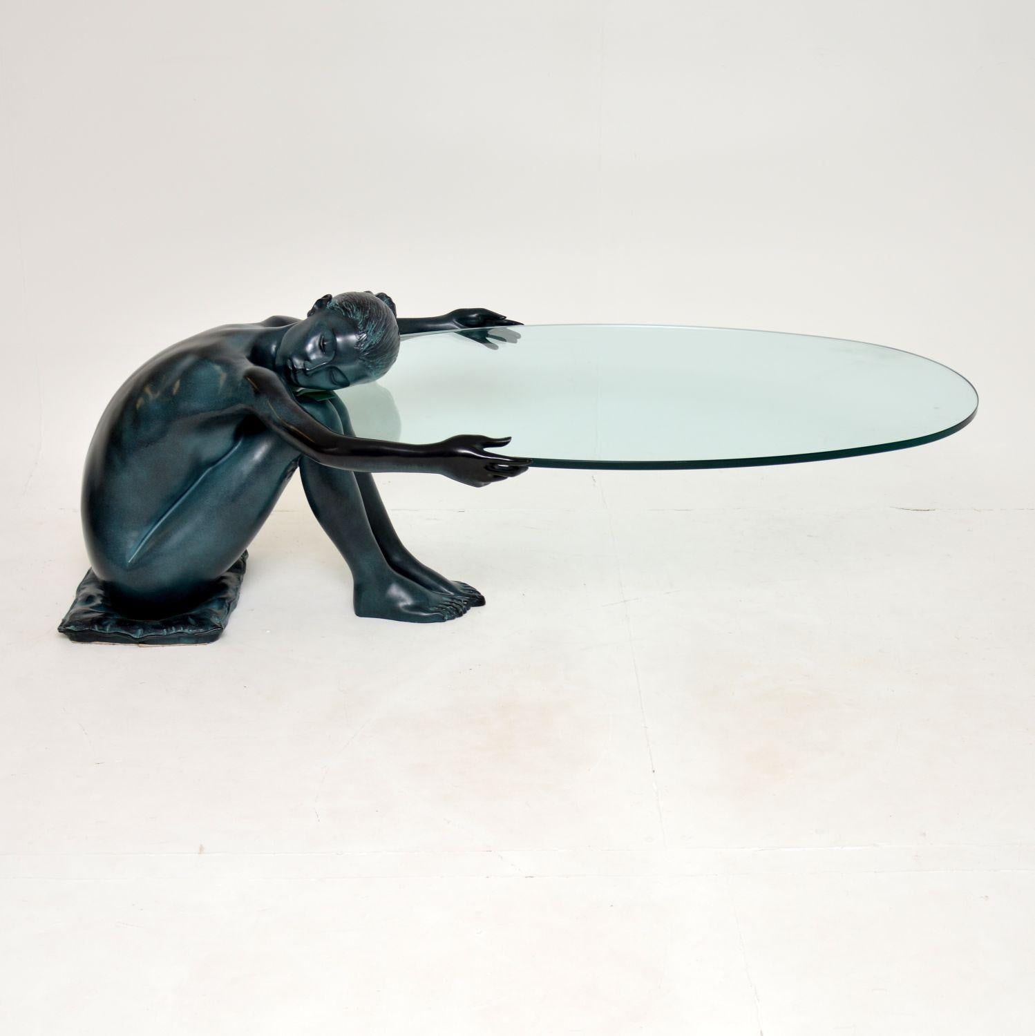 Une table basse étonnante et très impressionnante:: à l'image d'une dame tenant le plateau en verre. Il s'agit d'une pièce remarquable:: datant probablement des années 1970-1980. 

La dame est très lourde et fabriquée en fonte ou en un autre métal::
