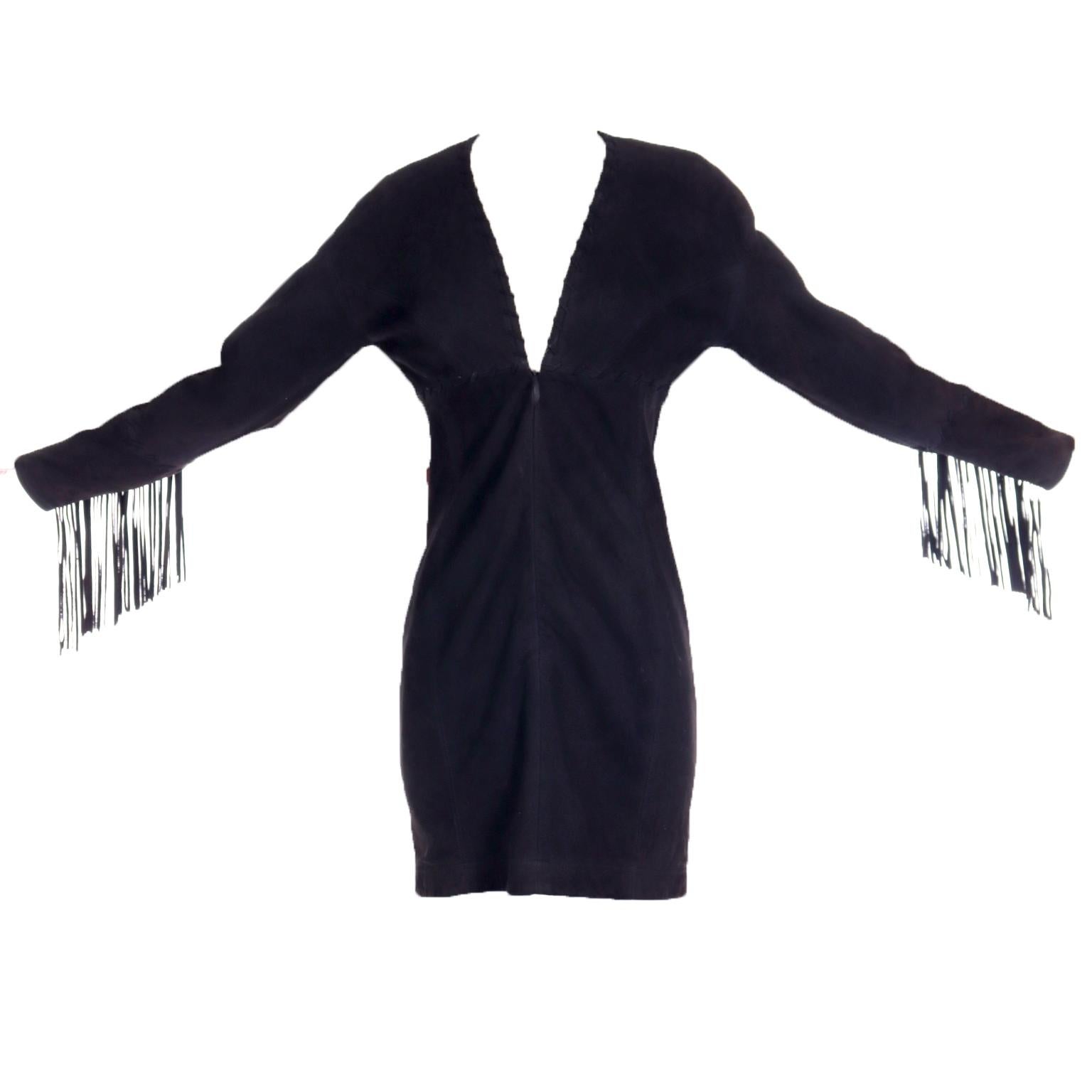 This vintage late 1980's or early 1990's Isaac Mizrahi mini dress is in a luxurious black lambskin suede and features fringe at the lower portion of the sleeves. This dress has unique topstitching along the neckline and sleeves and closes with a