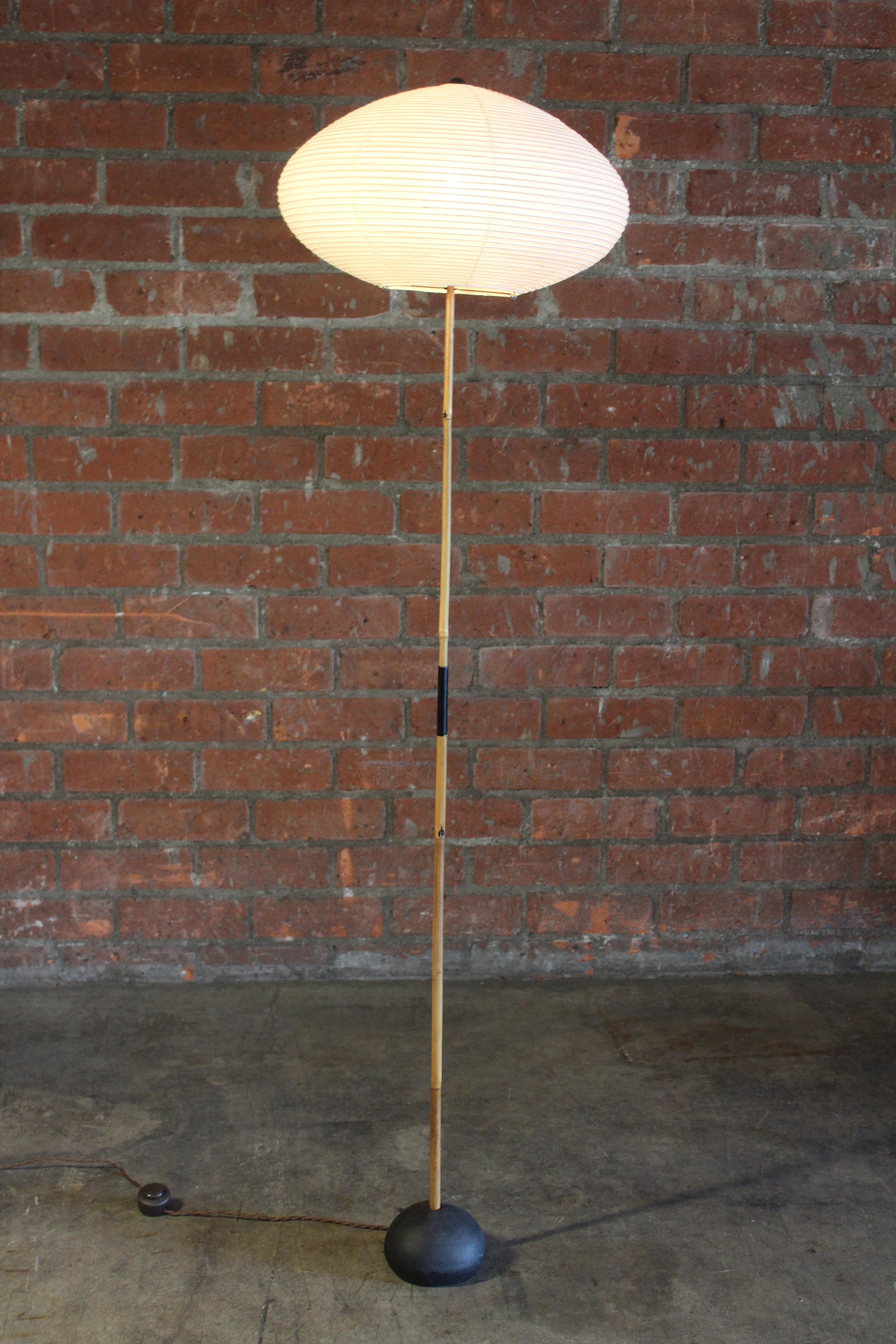 A vintage Akari floor lamp by Isamu Noguchi, Japan, 1960s. Features a bamboo stem with an iron 