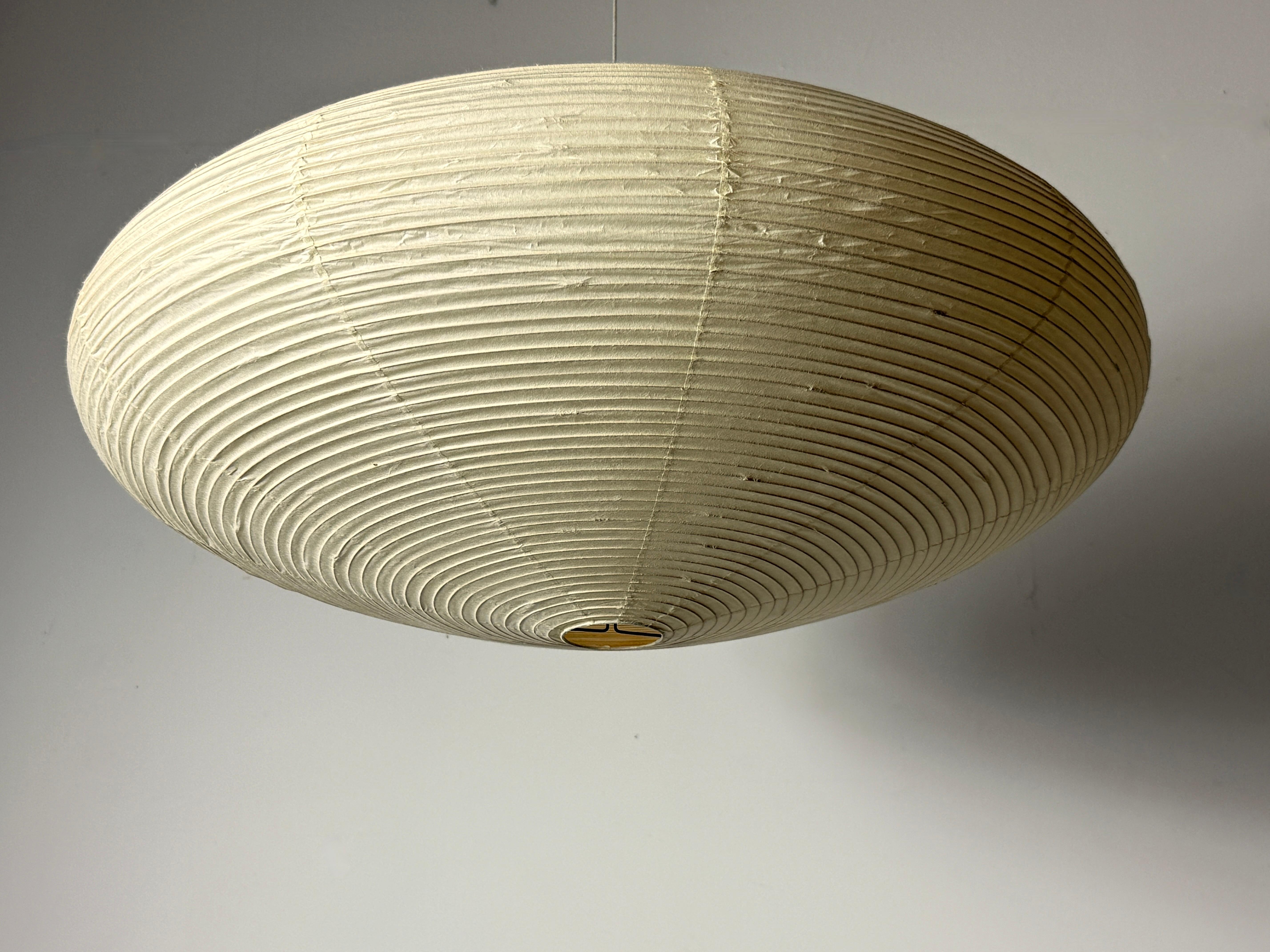 Vintage unused model 21A Akari light sculpture by Isamu Noguchi 
Manufactured in Gifu Japan by Ozeki circa late 1970s

Handmade shade of washi paper over bamboo ribbing with sun and moon stamp marked Japan and signature

Never used, complete with