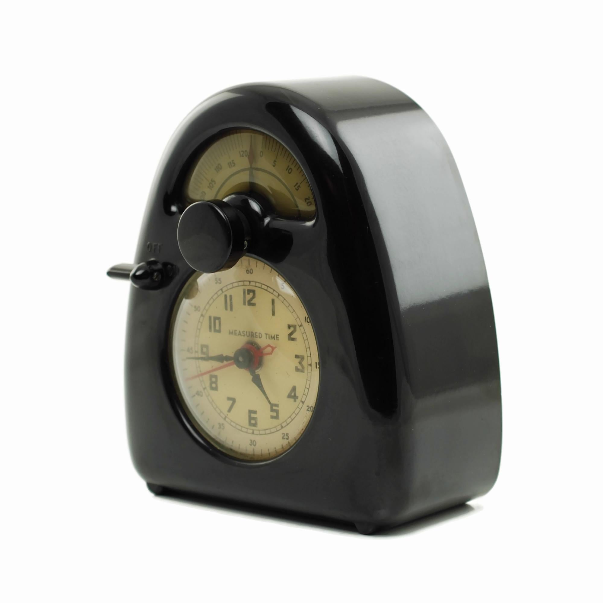 This circa 1930s Hawkeye electric clock timer was designed by noted sculptor, landscape artist and industrial designer Isamu Noguchi (1904-1988). The piece features a shiny black bakelite arched case and has a large round clock face with a domed