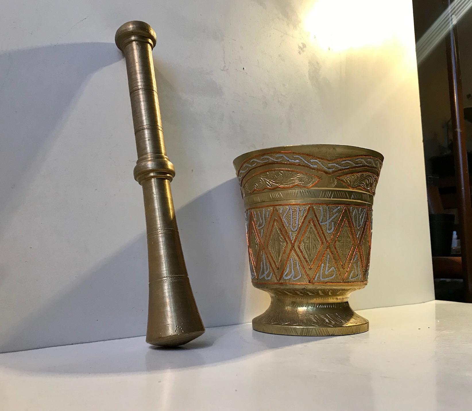 A large decorative Mortar and accompanying Pestle. The mortar is made from solid hand-engraved bronze with in- and on-lay in silver and copper thread. Harlequin patterns and Islamic text are also present around its perimeter. It was manufactured by