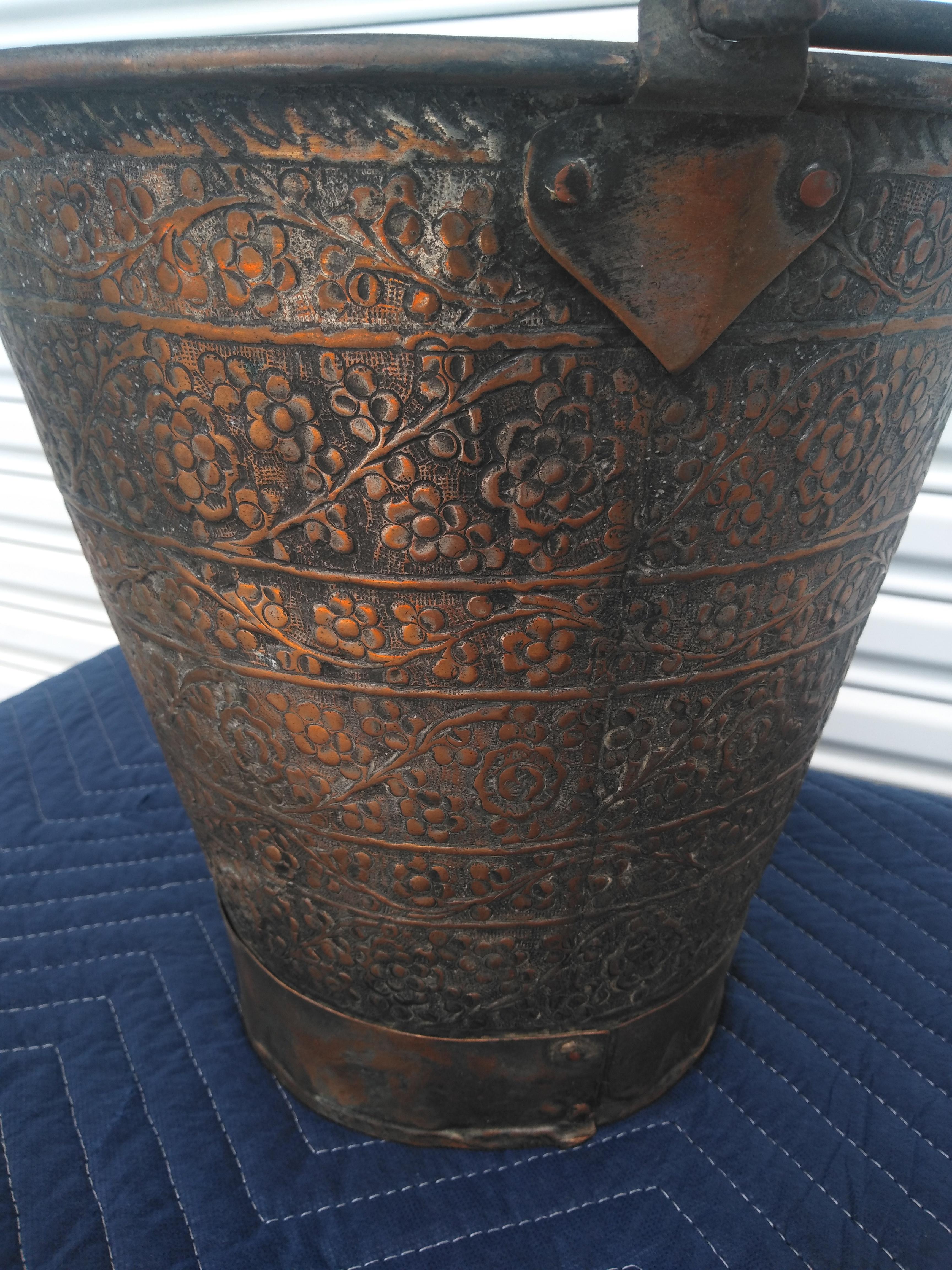 This hand forged metal pail has a heavy steel handle. The design is all hand crafted. It has a really nice patina and would make for a nice decorative object.