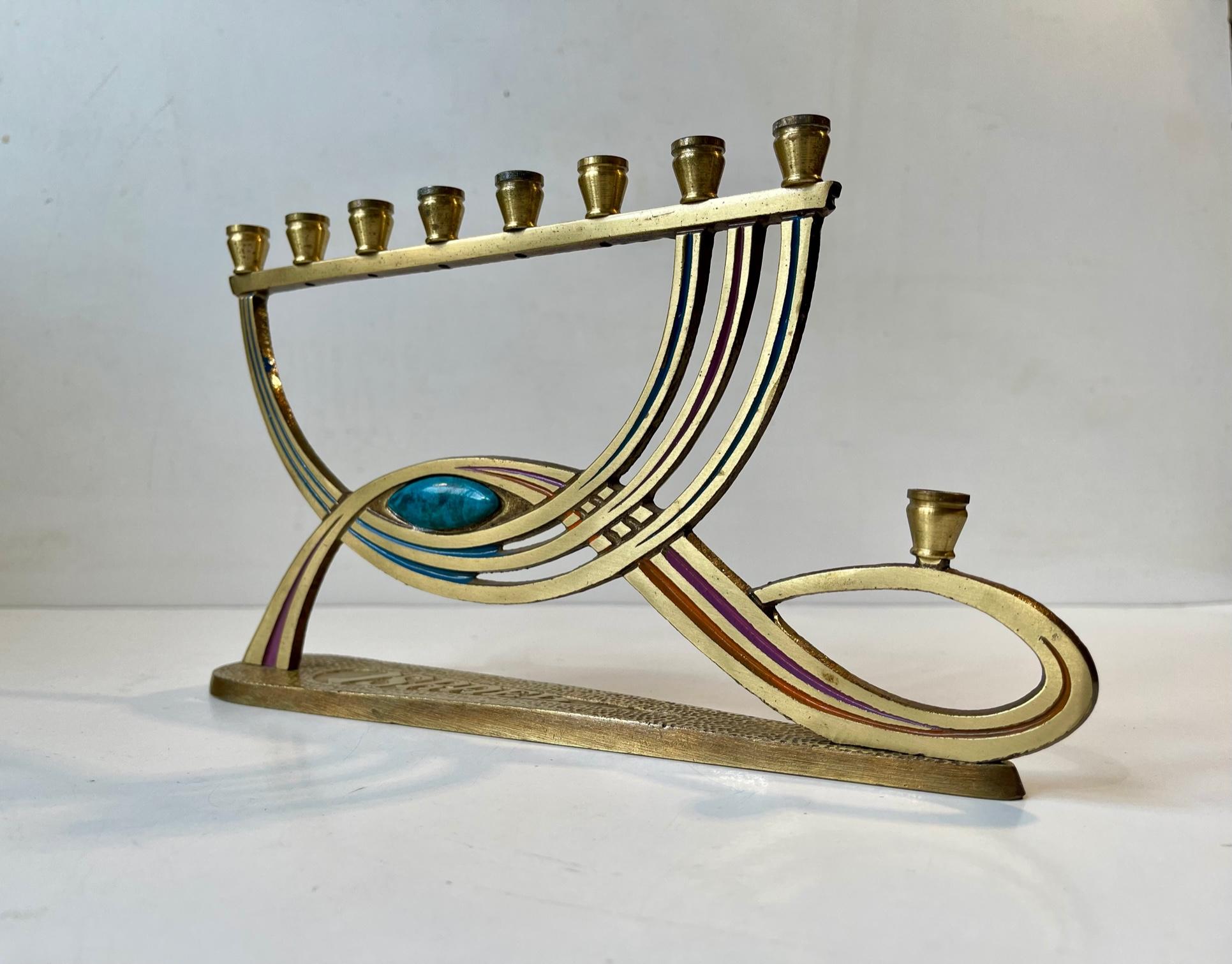 Small intricate brass Chanukah Candelabra manufactured by Tamar in Israel in 1966. Distinct and characteristic Art Deco revival styling. Hand-painted and jeweled with a turquoise stone (possibly green Eilat). It takes 9 taper candles. Stamped: