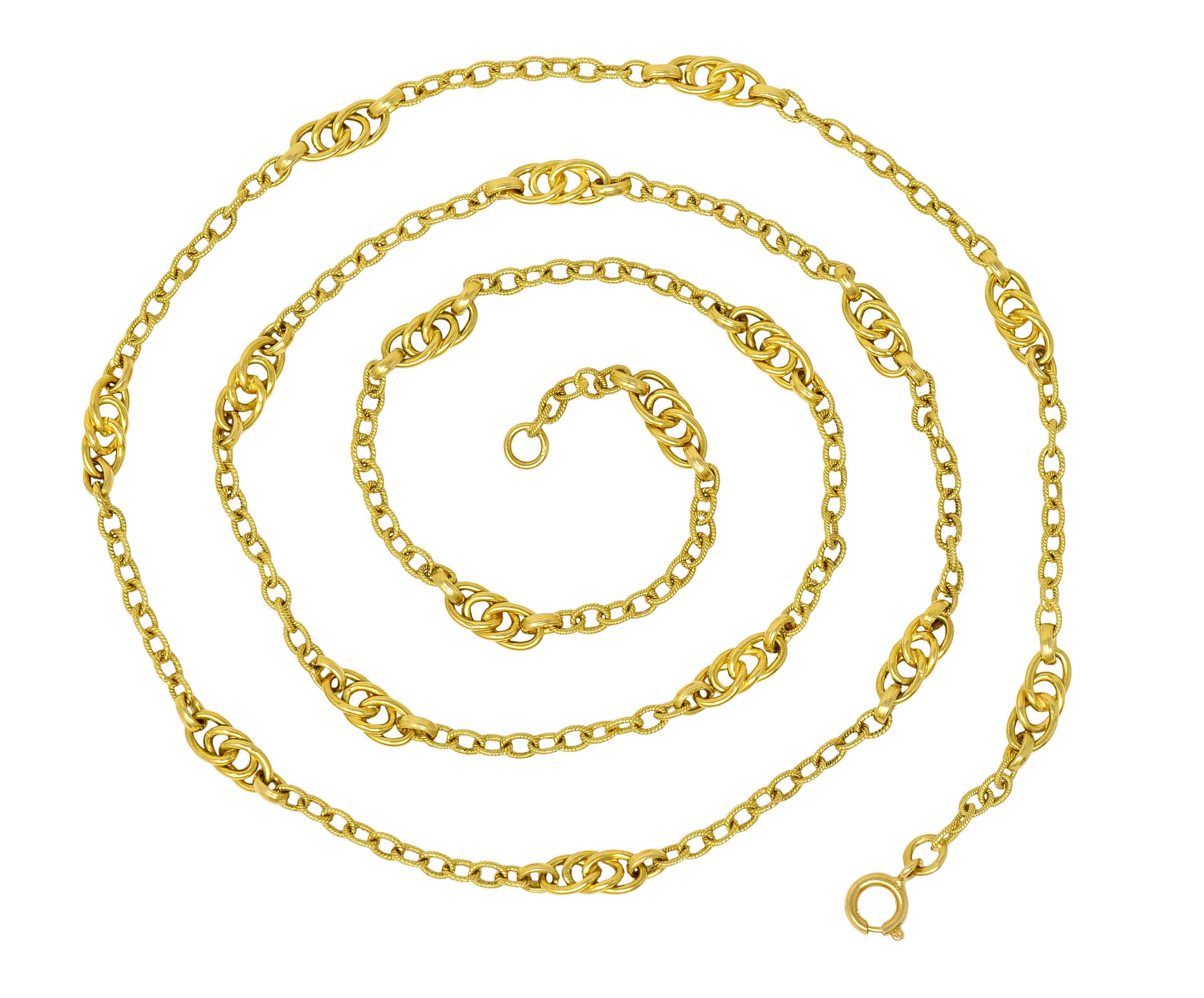 Long chain necklace is comprised of textured curb links

With high polished tri-looped stations evenly spaced throughout

With Italian assay marks for 18 karat gold

Circa: 1990s

Length: 30 1/2 inches

Width at widest: 1/4 inch

Total weight: 29.8