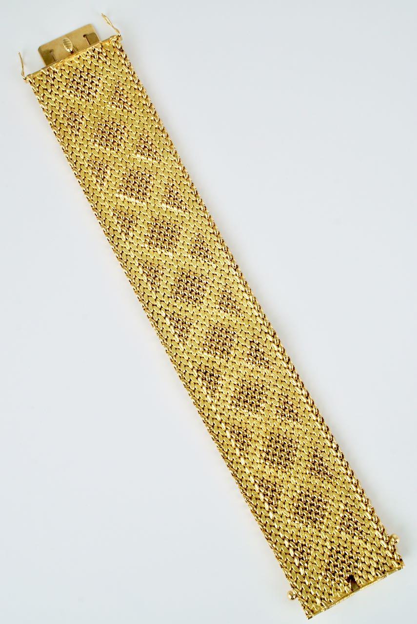 A beautifully executed bracelet of a wide 18k yellow gold mesh design that has then been rolled or stamped to produce a fabric like effect of a geometric pattern of shiny stitch or bead like links above a matt ground. Finished with an integrated box