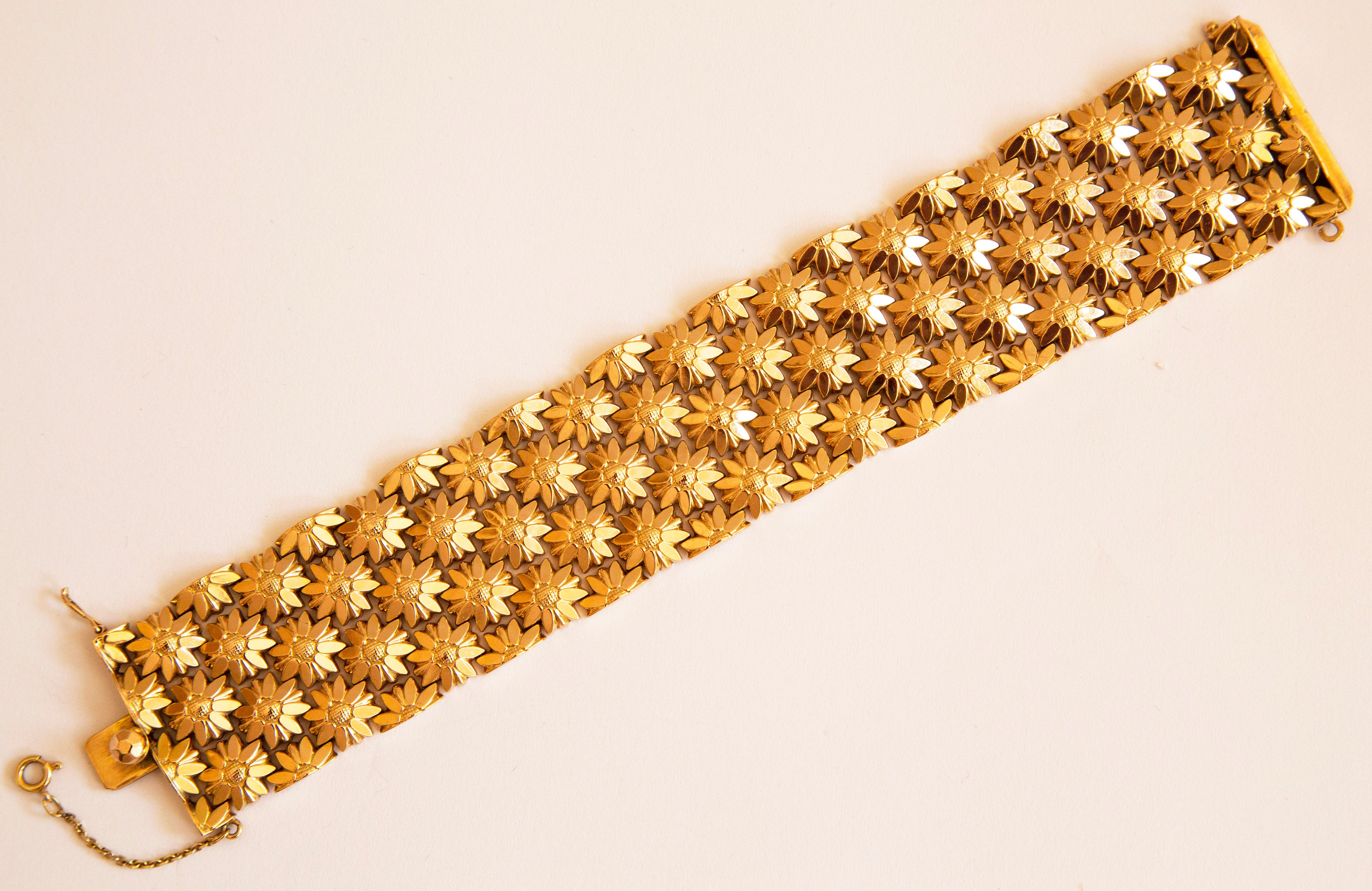 A vintage Italian wide link bracelet manufactured in the late 1970s. The bracelet is made of 18 karat yellow gold and it features  floral (sunflowers like) motifs. The bracelet can be closed with a box lock and in addition it has a safety lock clasp
