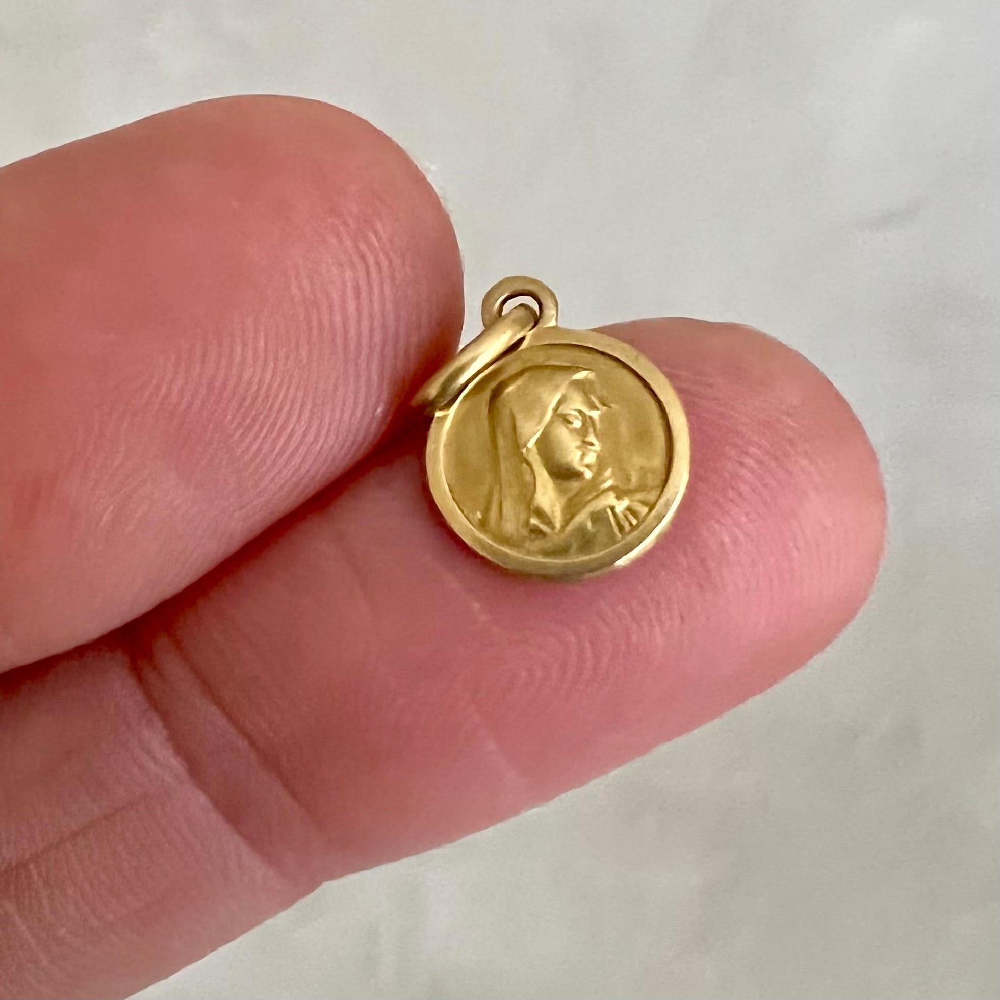 An Italian 18 karat gold Virgin Mary coin charm pendant. This 1950's small coin charm has a beautiful design with Virgin Mary depicted in relief in the middle. Charms are great to collect as wearable memories, it has a symbolic and often a