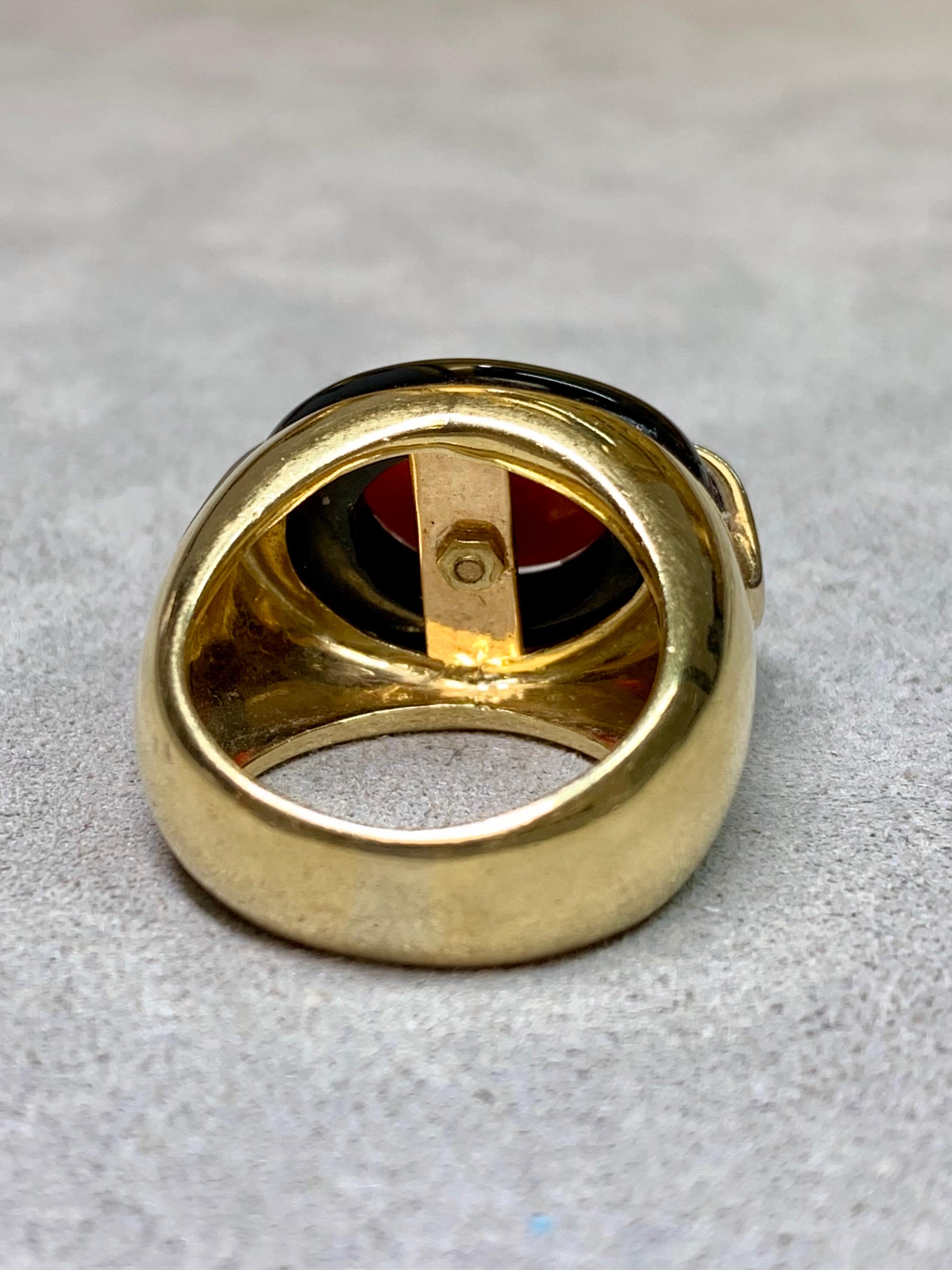 
Un llamativo anillo italiano vintage de los años 90, magistralmente elaborado en oro amarillo de 18 quilates. El diseño presenta un cabujón de coral rojo ricamente coloreado engarzado en una pieza tallada de ónice negro brillante, que a su vez está