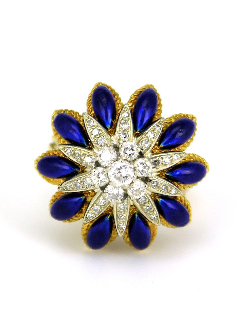 A bold domed ring with a central cluster of 7 round brilliant cut diamonds surrounded by a further 30 single cut diamonds in a star design; the points interspersed with domed marquis panels of royal blue enamel mounted on a tapered four row wire
