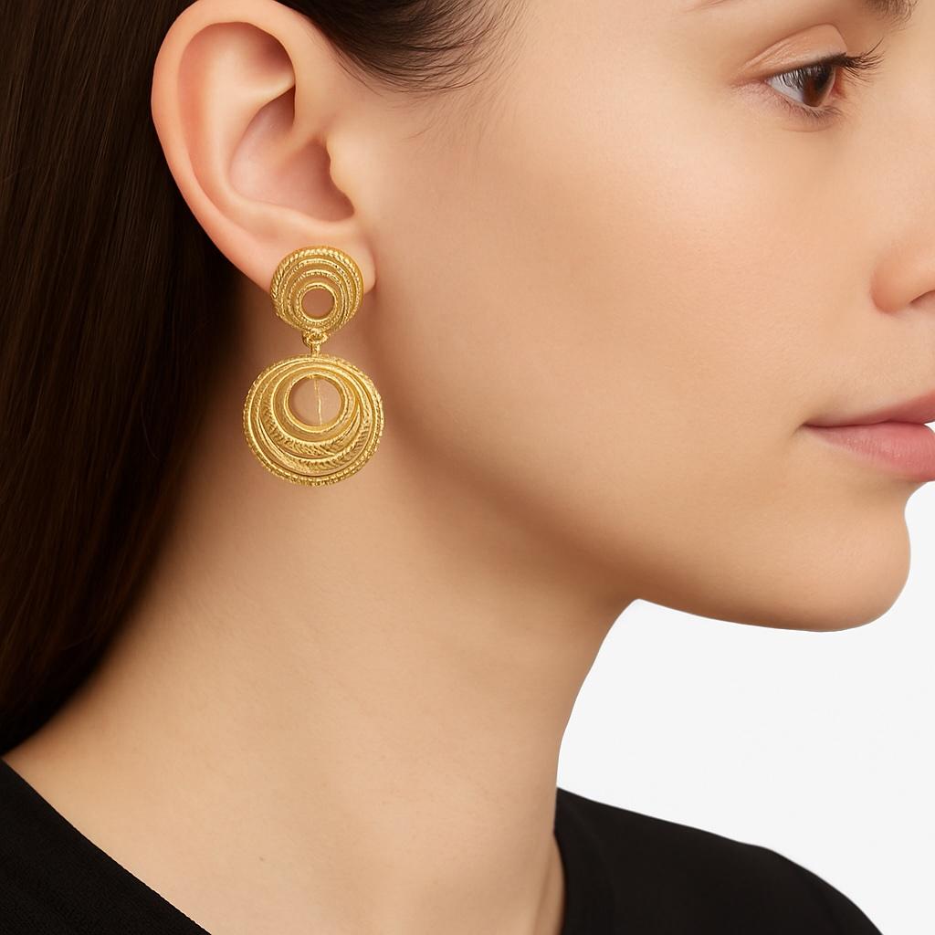 Un hermoso par de pendientes vintage italianos en oro amarillo macizo de 18 quilates, con un diseño de círculos concéntricos e intrincados detalles texturados. Estos pendientes esculturales muestran círculos calados en capas que crean un movimiento