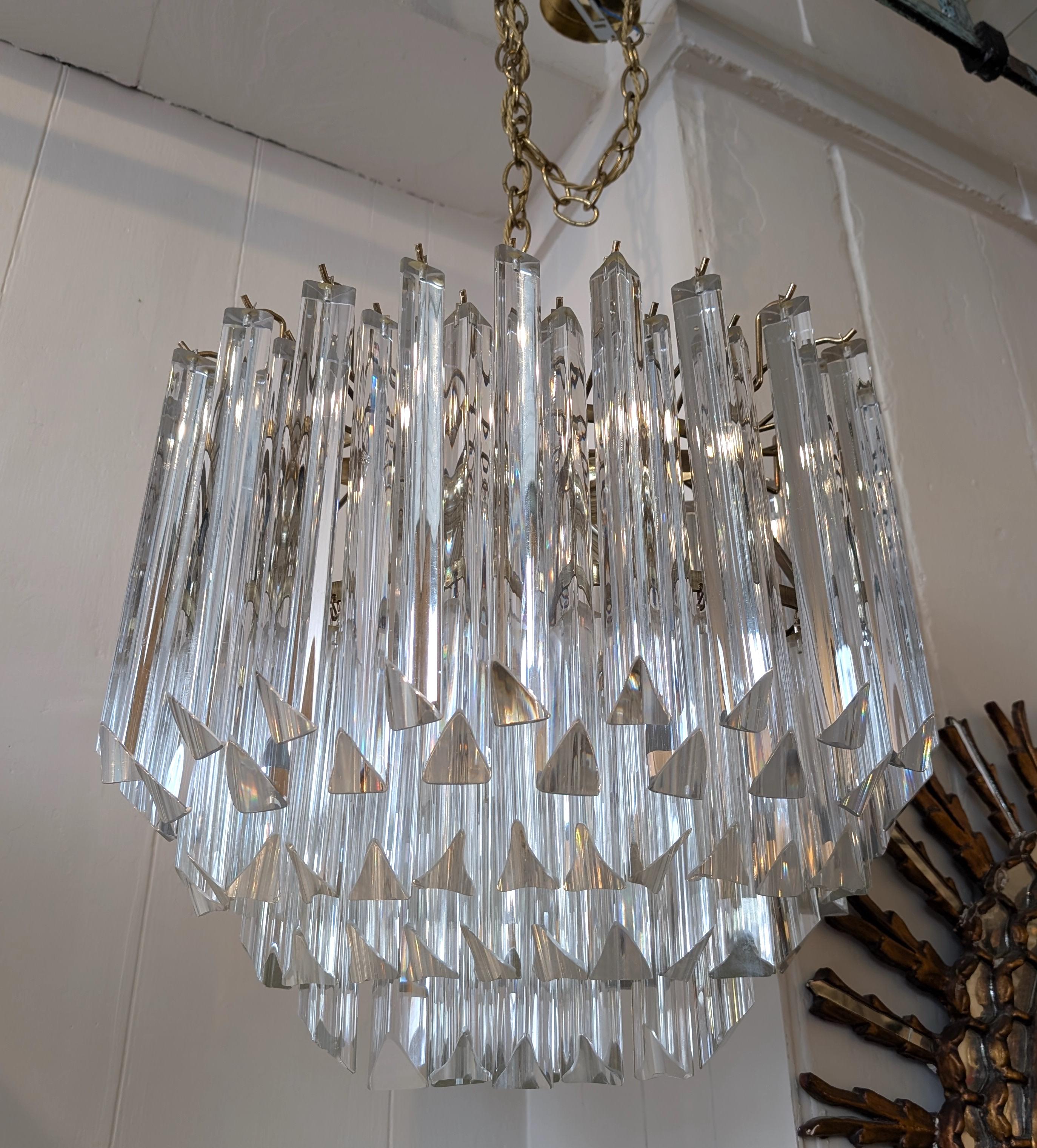 Lampadario ovale vintage in stile Venini degli anni '70. Densa di bacchette di vetro triangolari sfaccettate su una struttura in metallo dorato. Non è rimasta l'etichetta del produttore. Alcune piccole scheggiature superficiali su un paio di aste.