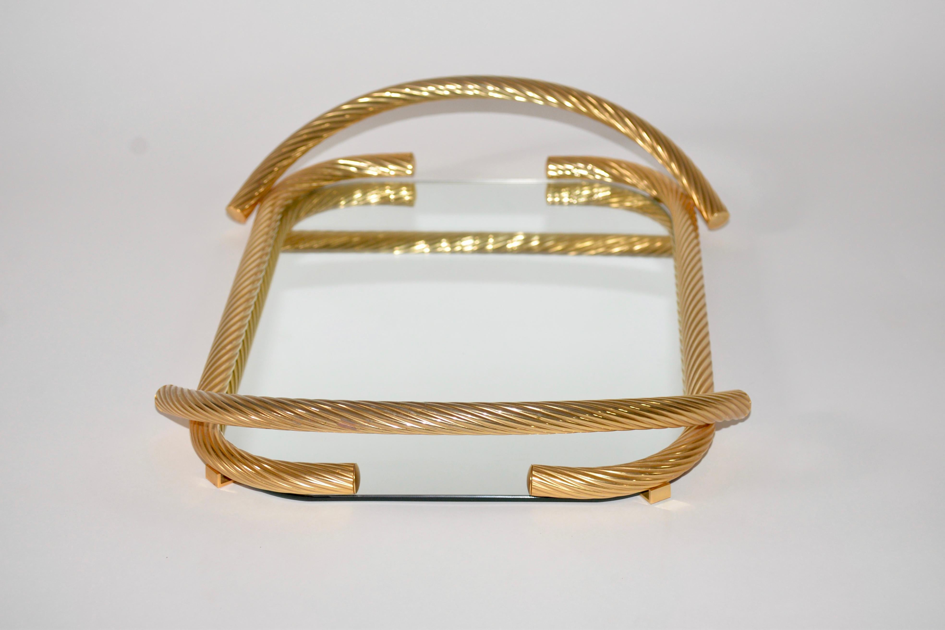 A fabulous 24-carat gold-plated vintage Italian serving tray in the Hollywood Regency style. A lovely rope twist effect detail on the brass work with a mirrored glass top.
 


 