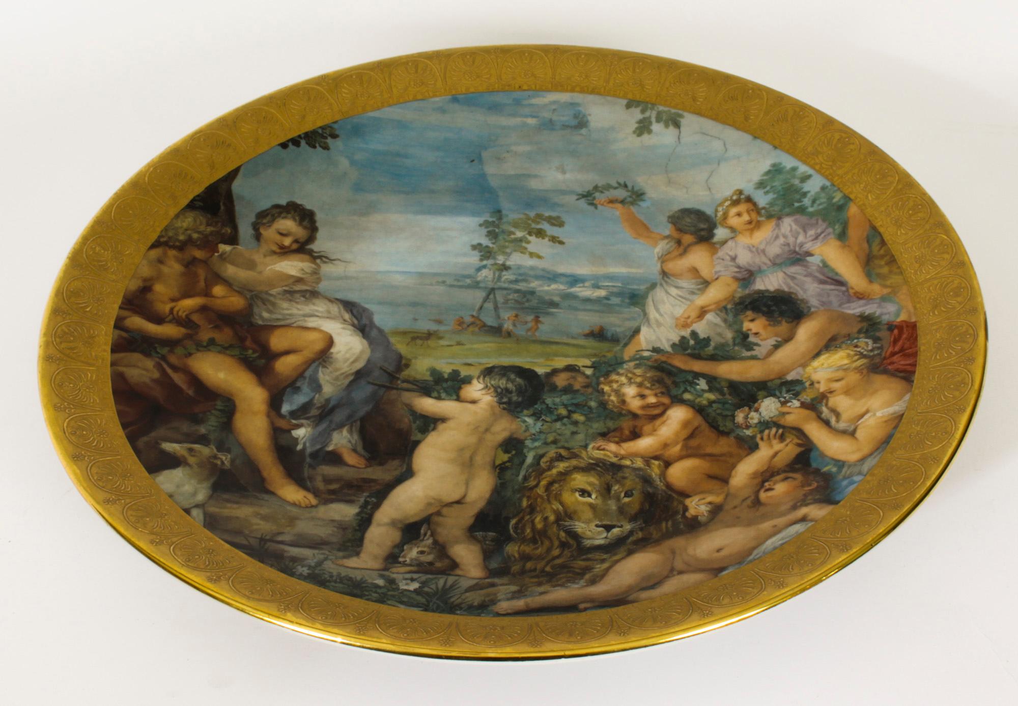 This is a beautiful huge vintage Italian porcelain charger, Circa 1950 in date.

This colourful and decorative scene depicts a group of maidens and care free cherubs with a lion set within a gilded embossed border.

The charger rests upon a