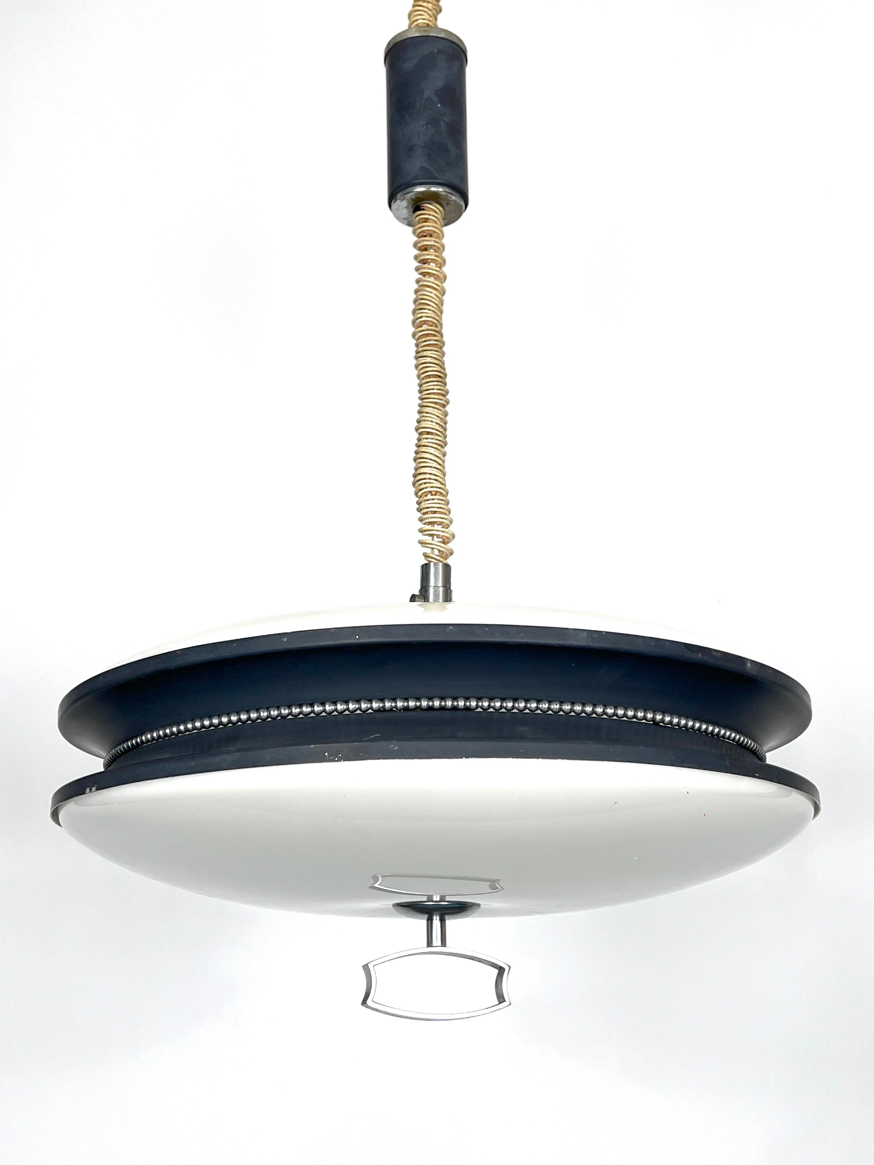 Bon état vintage avec traces d'âge et d'utilisation pour cette lampe suspendue à hauteur réglable produite par Reggiani pendant les années 60. Il est réalisé en métal laqué noir et en plexiglas blanc. Le mécanisme de réglage est entièrement