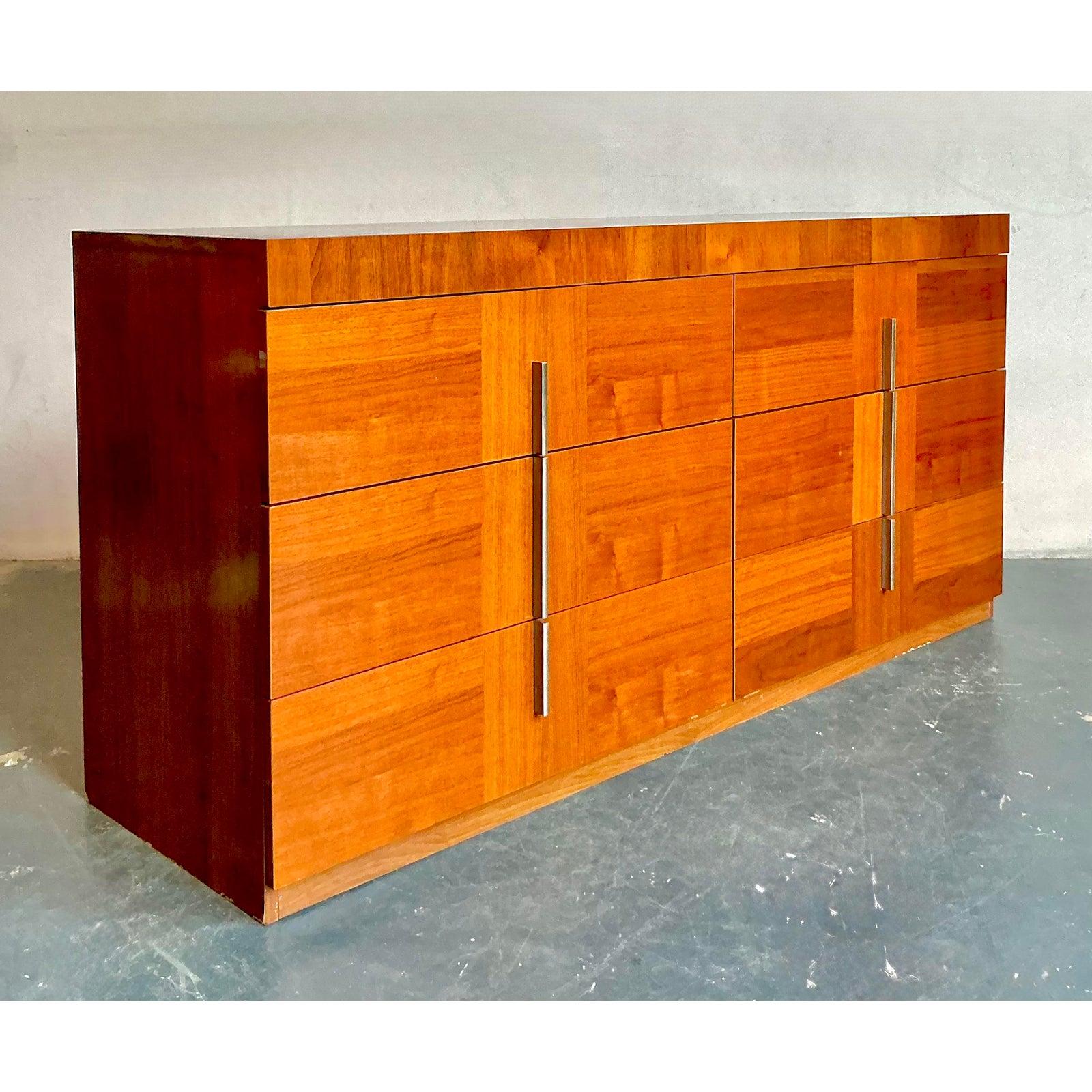 Ti presentiamo una splendida cassettiera vintage italiana di ALF, testimonianza del sofisticato design del Mid-Century Modern. Questo elegante pezzo è realizzato in legno di radica riccamente venato, che mostra i suoi ipnotici motivi naturali che